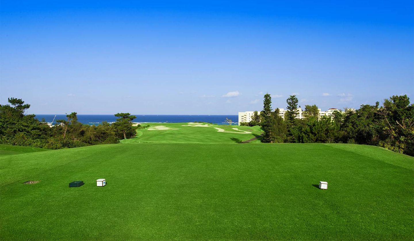 A manicured tee box leading to a well maintained fairway with coastal views