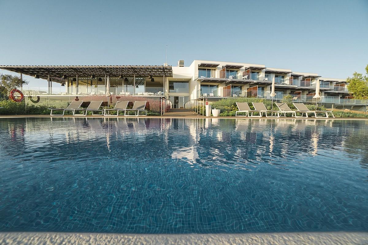 Outdoor swimming pool area with the Palmares Beach House Hotel in the background