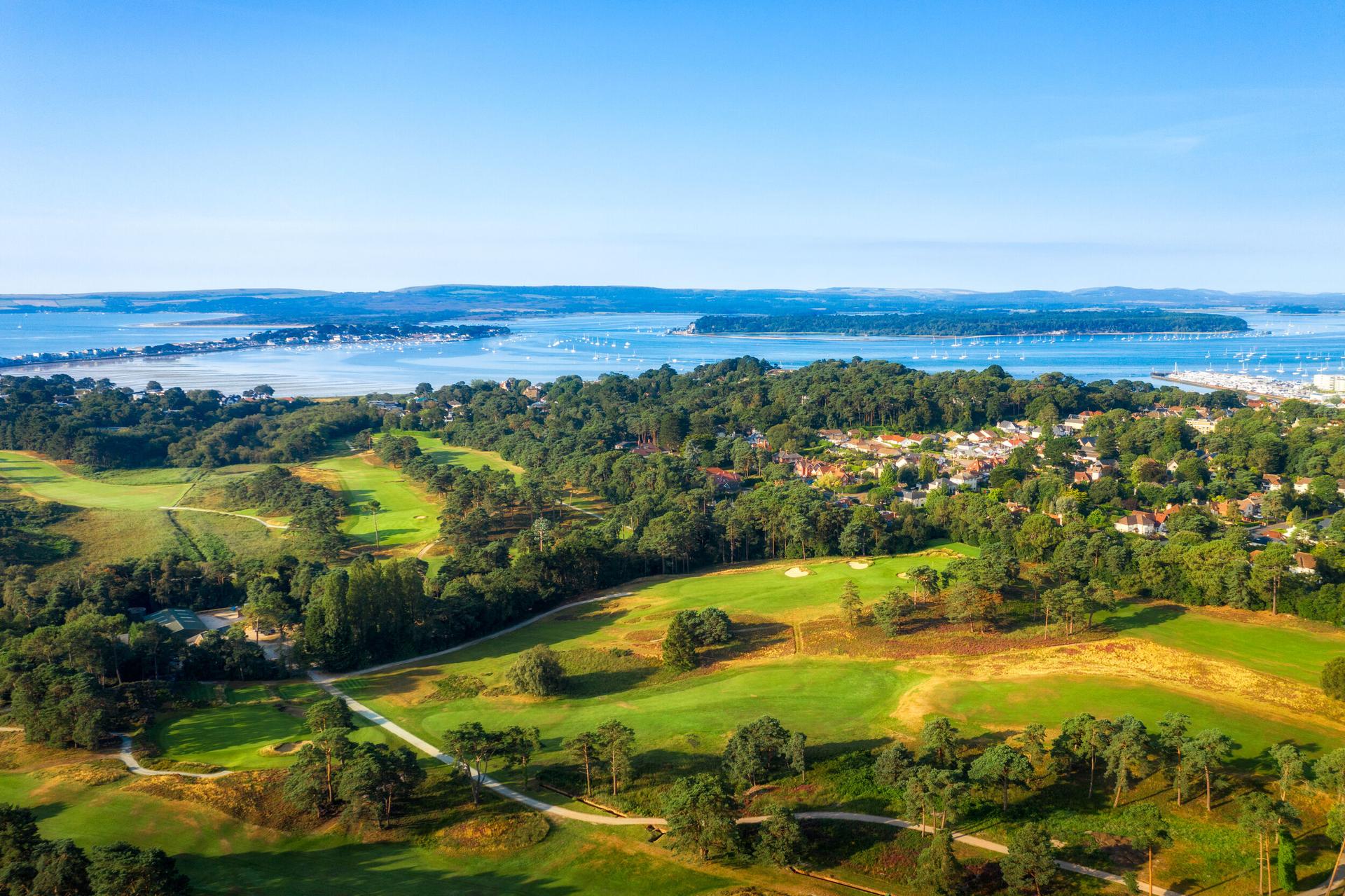 A scenic aerial view of the golf course near a bay with boats.