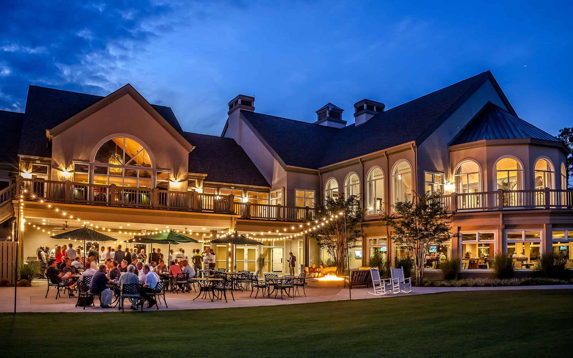 Exterior view of the Pinehurst resort building being lit up by overhead lights above the outdoor seating area
