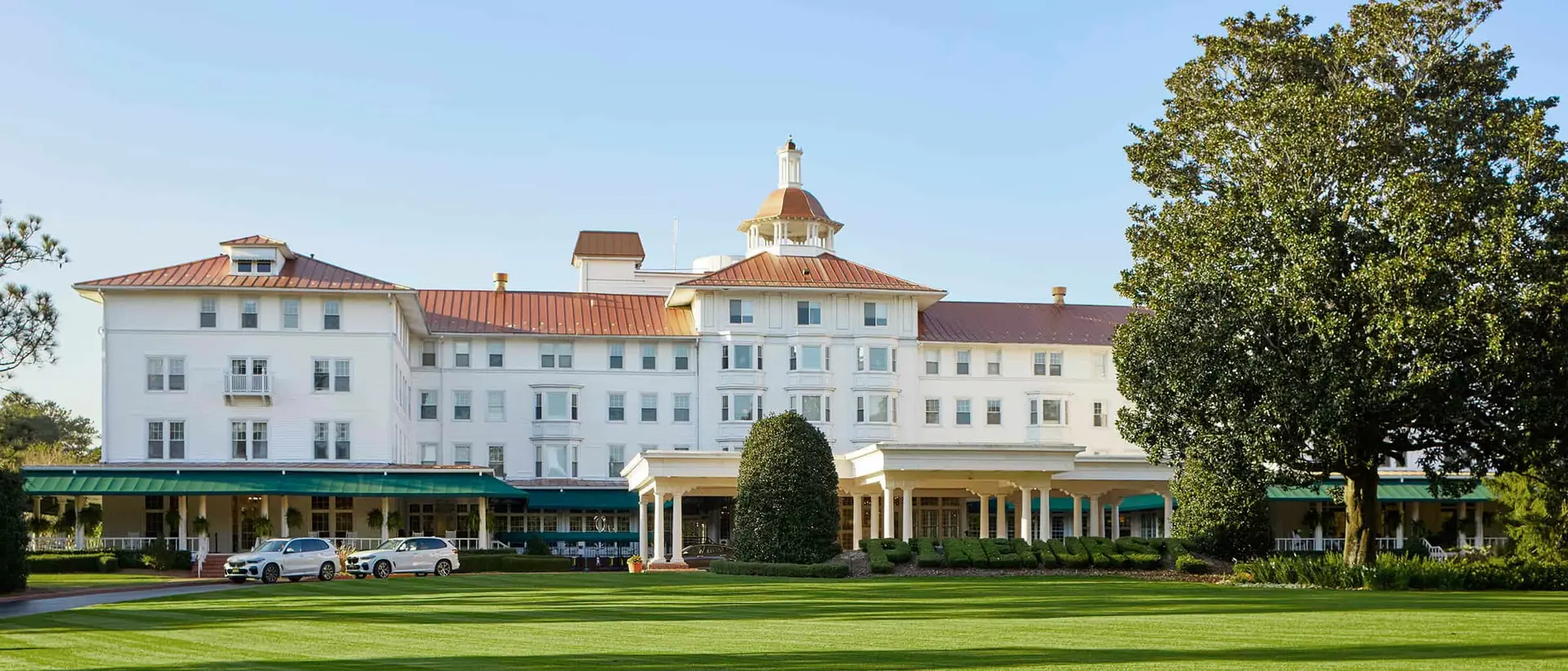 Wide angle shot of the front entrance to the resort with their name sculpted into a bush