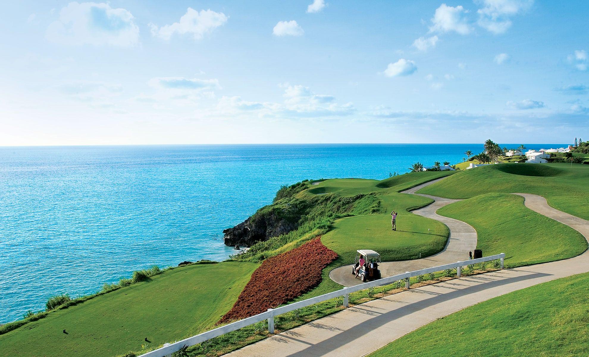 Golfer enjoying his round of golf with coastal views and his buggy parked on the stone walk path