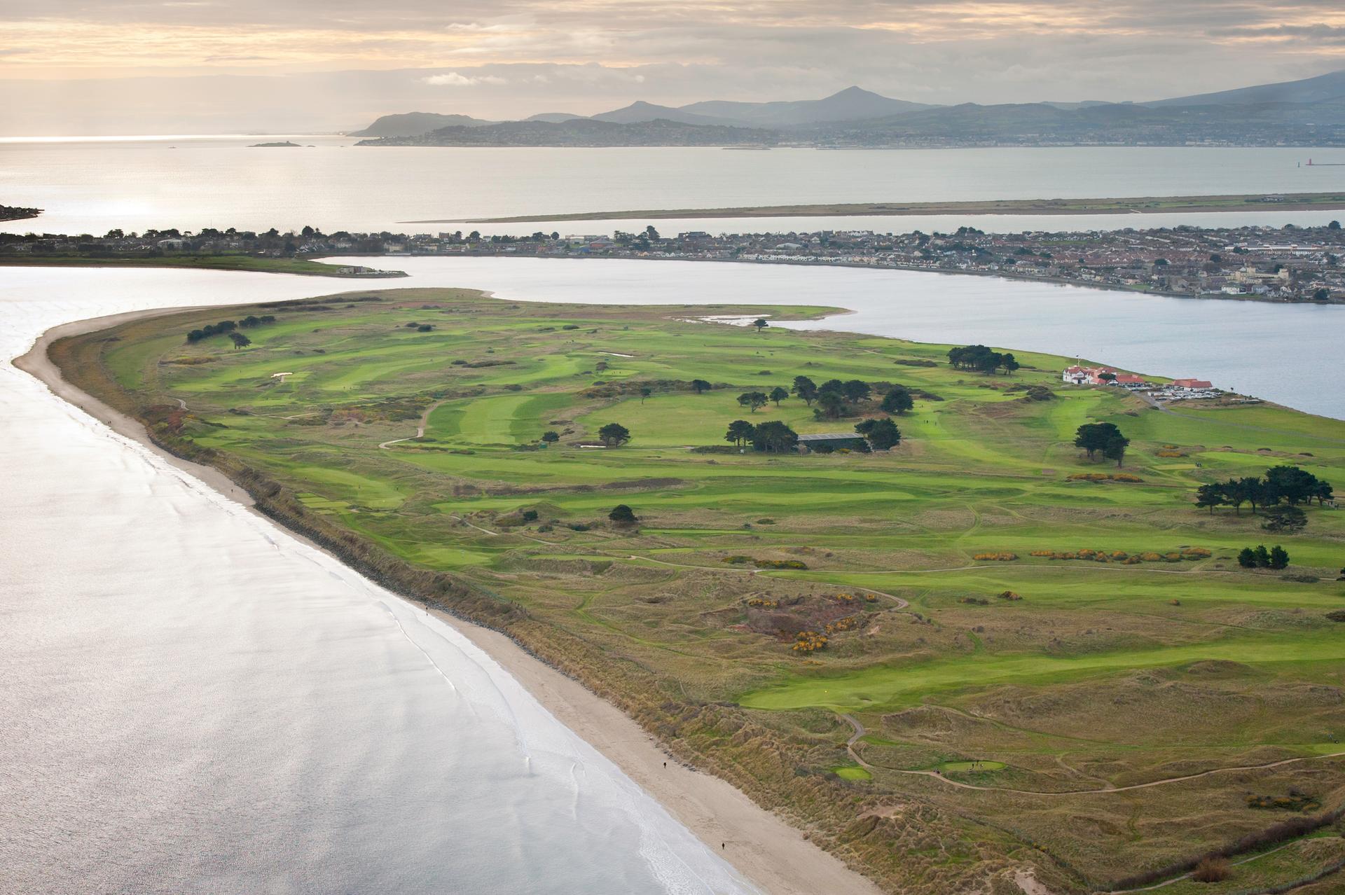 Aerial view of a golf course on a narrow peninsula surrounded by water.