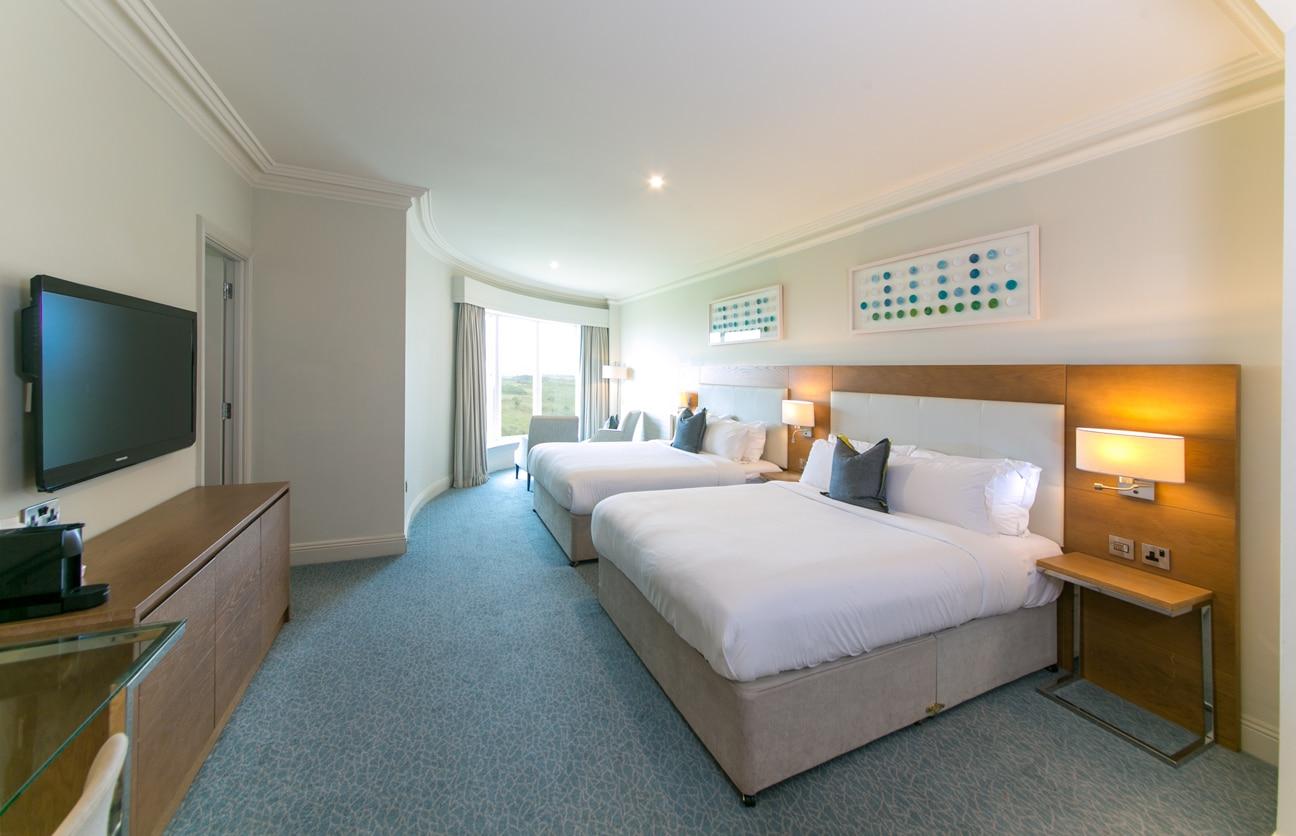 A spacious hotel room with two large beds and a modern design.