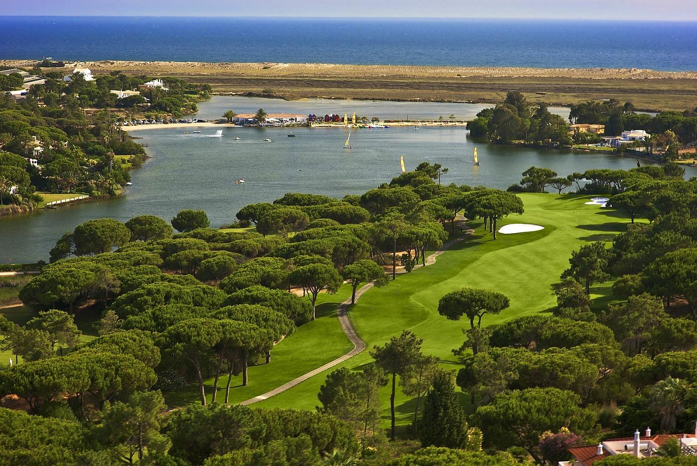 Aerial view of the undulating, tree-lined fairway with water at the end