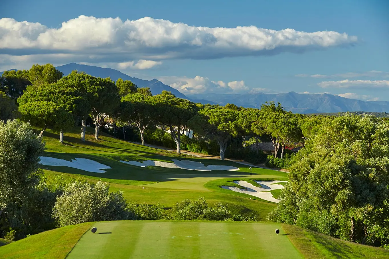 View from a tee box to a Par 3 green surrounded by bunkers