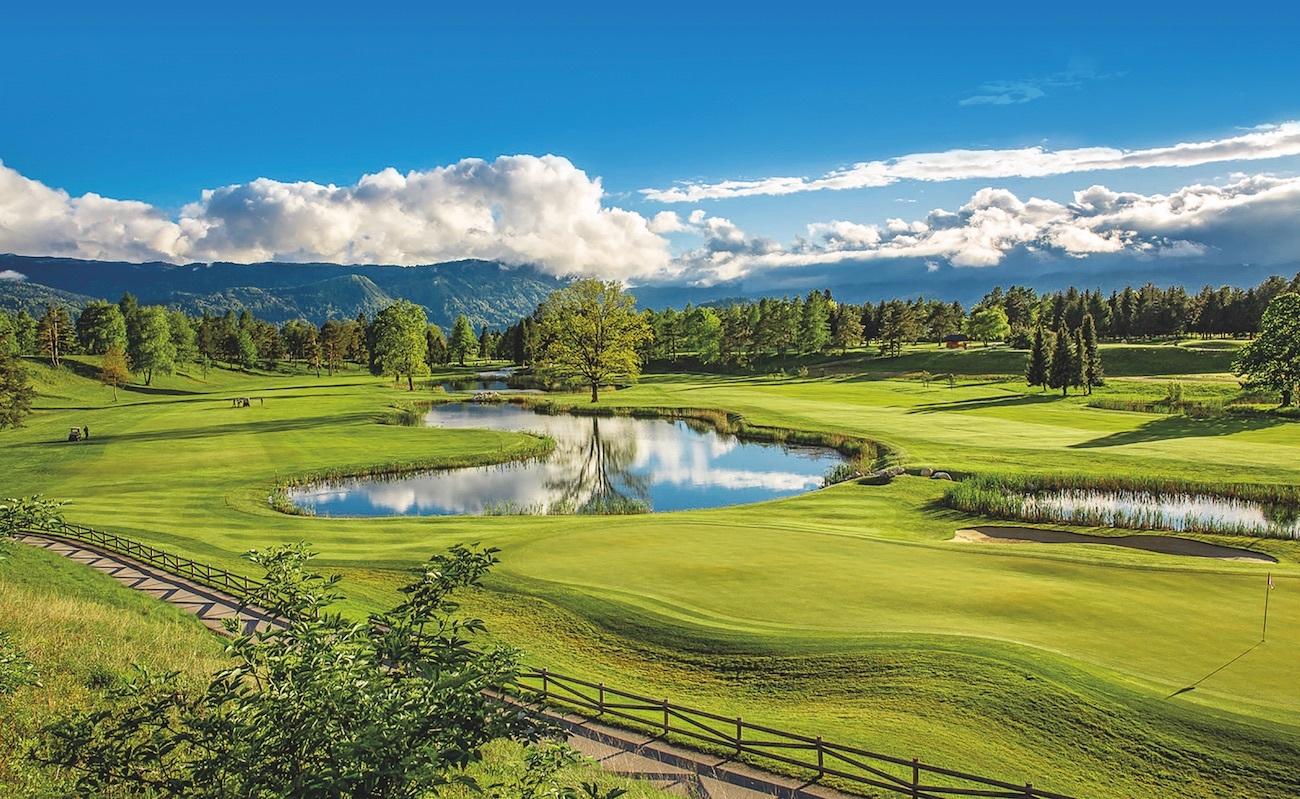 A lush golf course with reflective ponds and dramatic clouds in the sky.