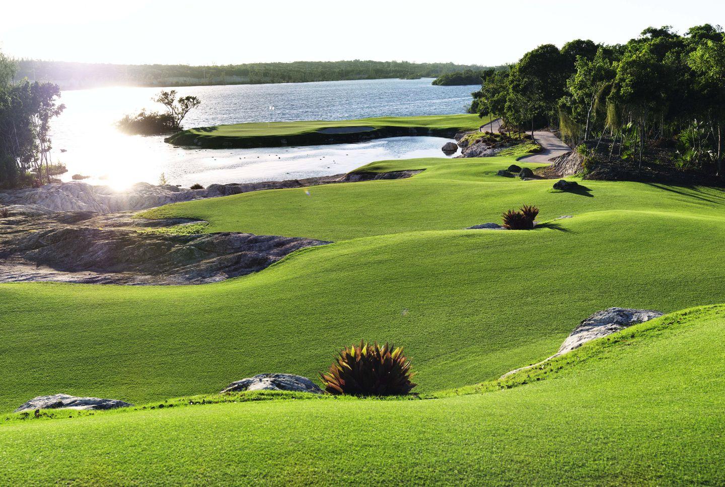 A rolling green fairway leading to a water-surrounded island green.