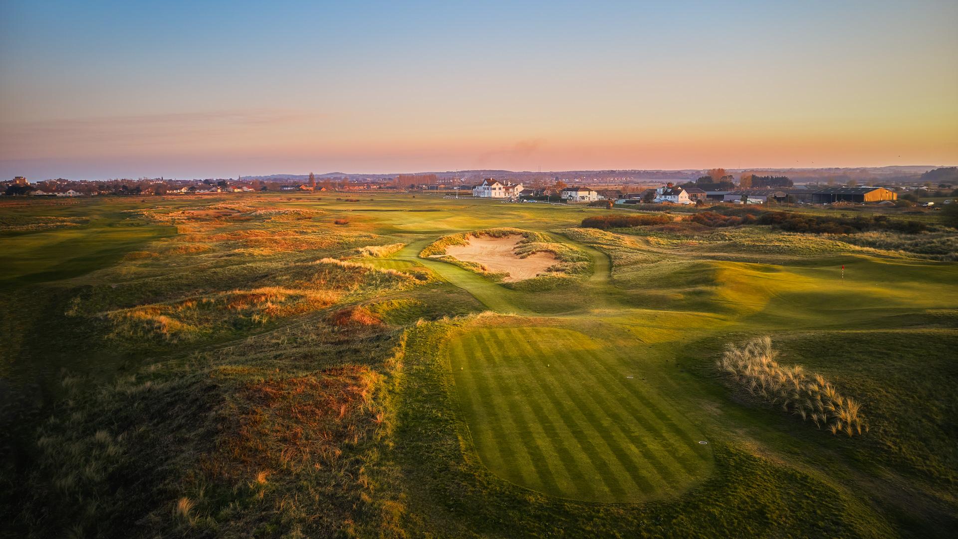 Evening view of a links course near a village.