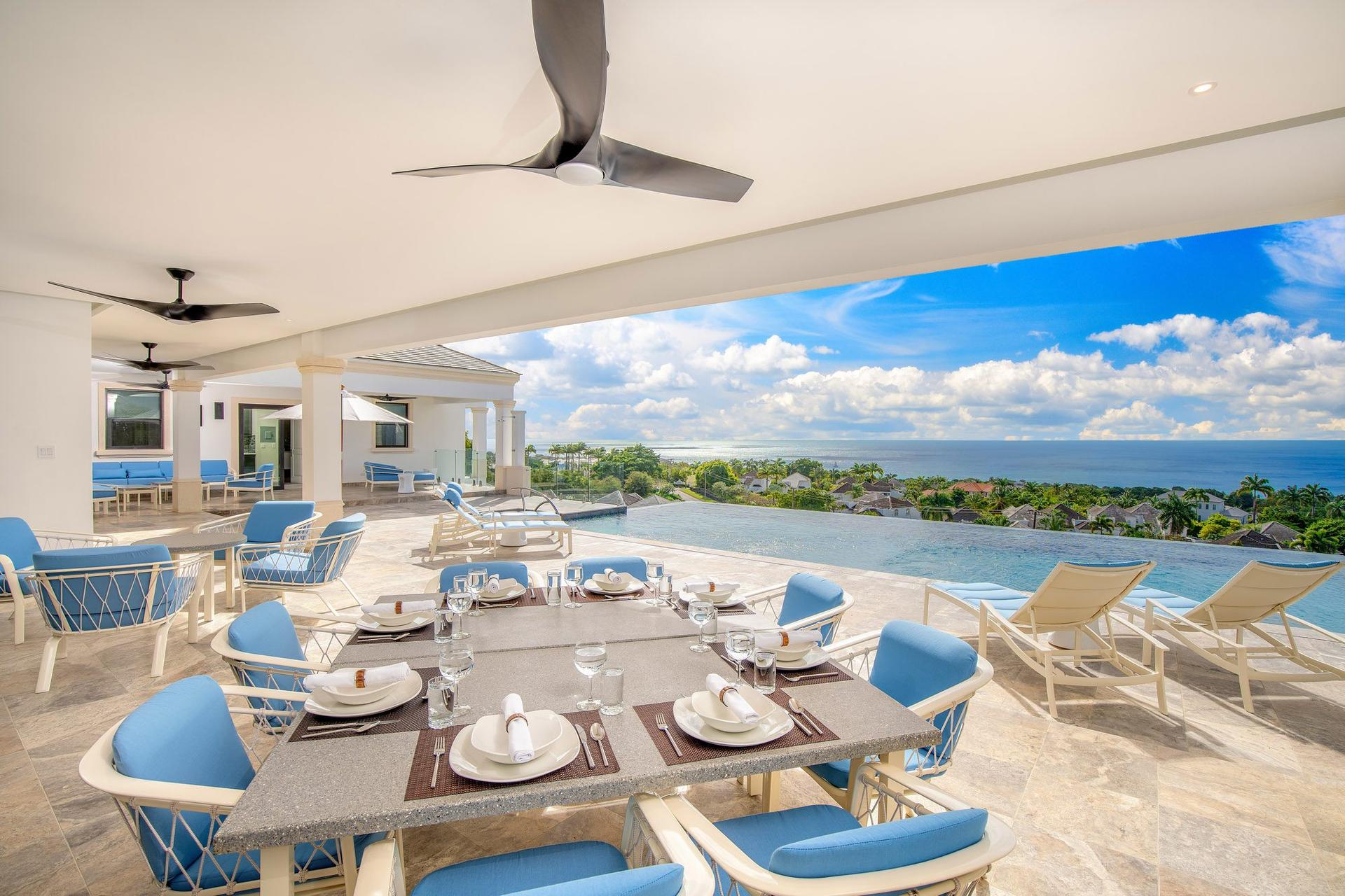 Pool side dining area and sunbeds with sea views