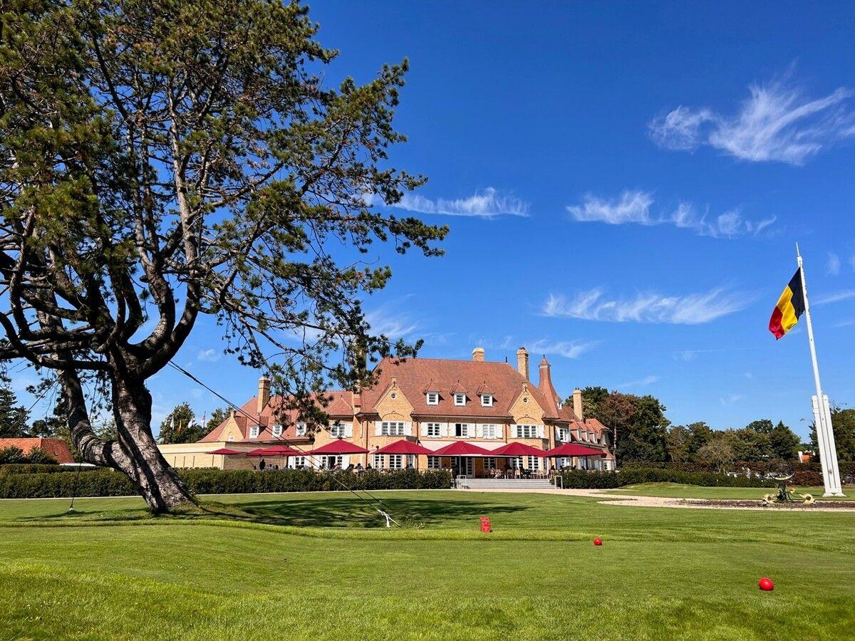 The Royal Zoute clubhouse overlooking a practice green with the Belgium flag towering over the course
