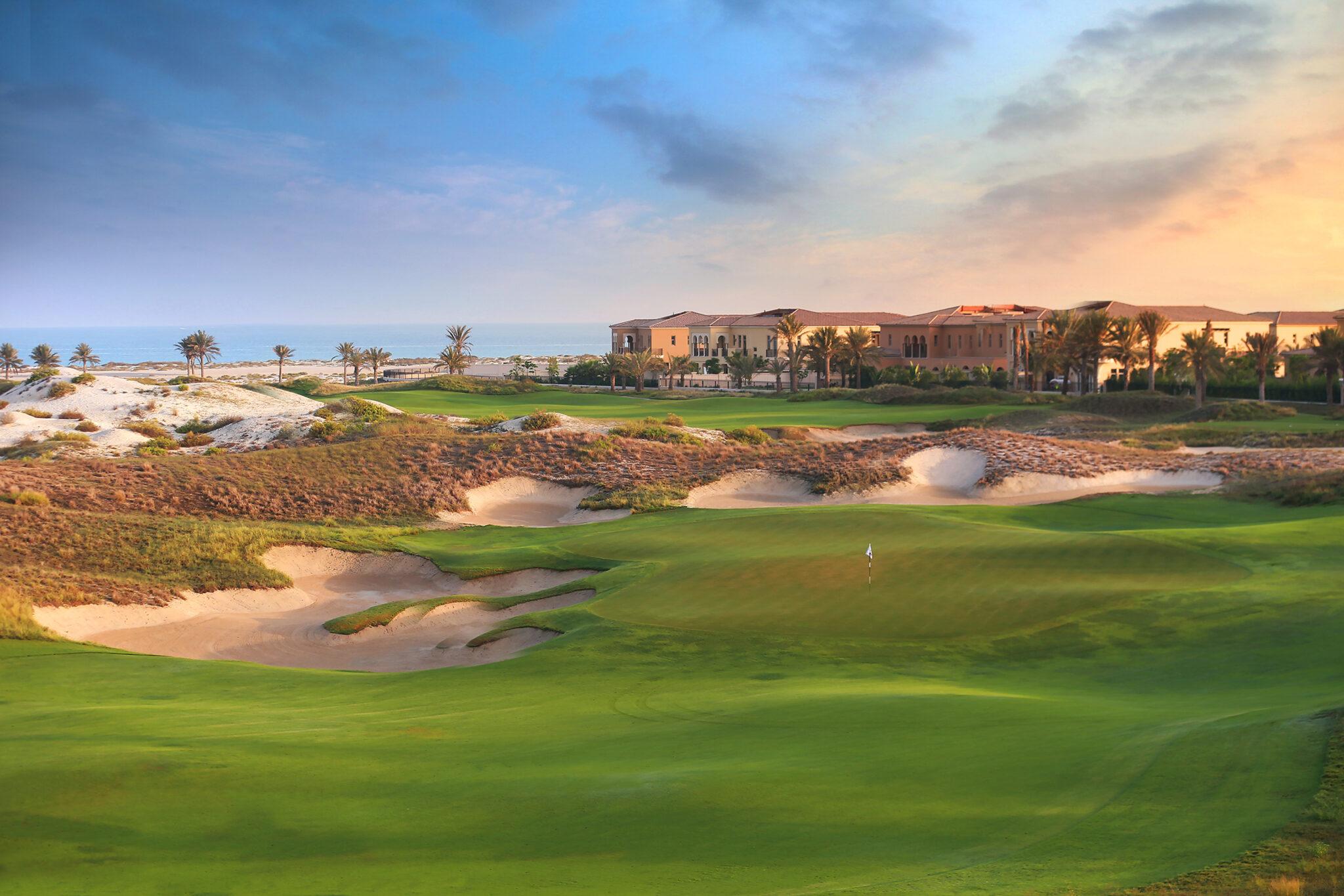 A smooth green surrounded by sand bunkers with coastal views