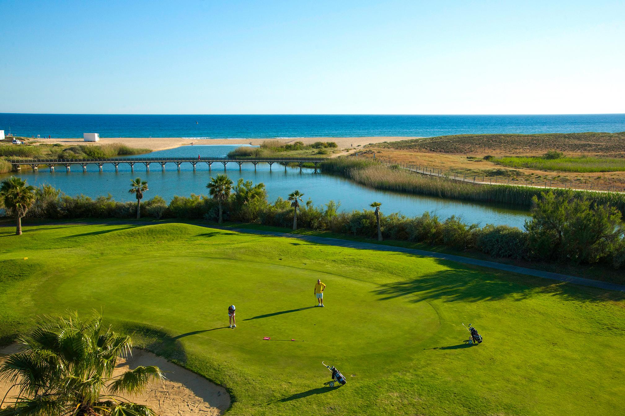 Two players on the green with the beach behind