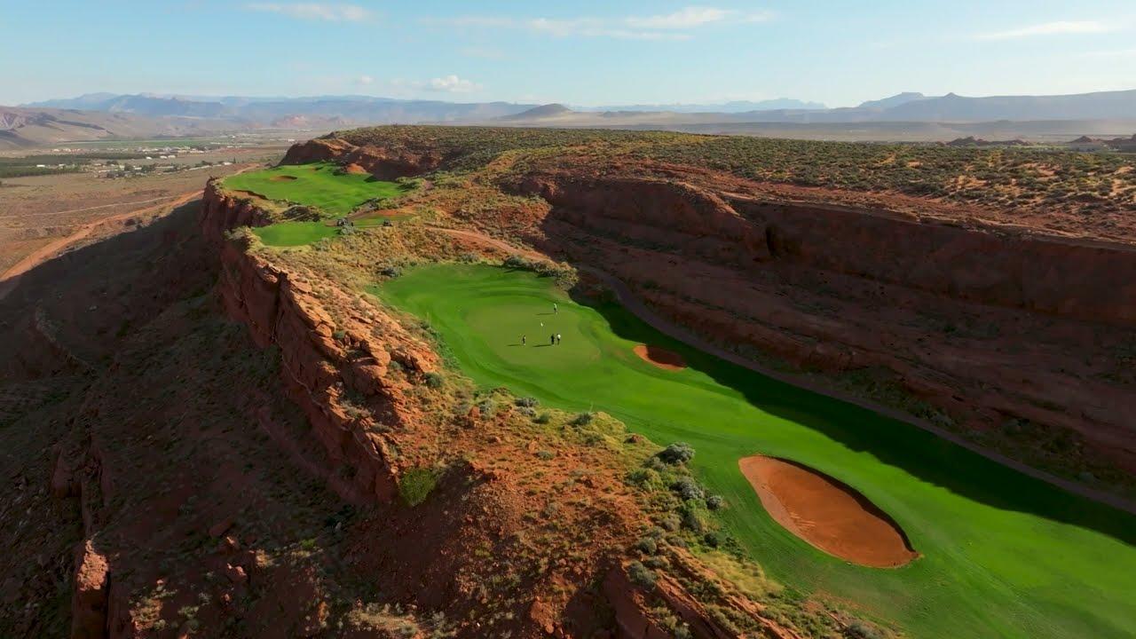 A golf hole carved between steep canyon walls with sweeping desert views.