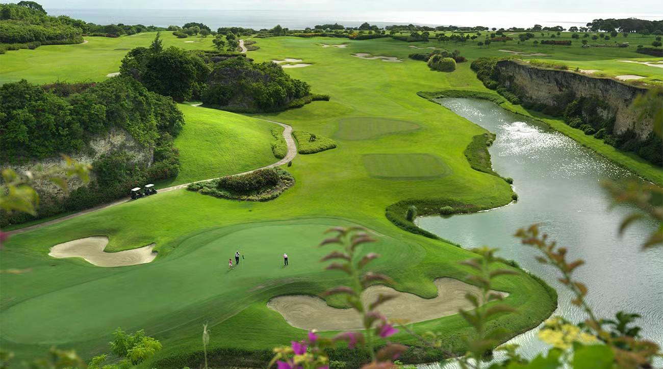 A breathtaking aerial view of Sandy Lane Resort’s golf course, featuring lush fairways bordered by steep cliffs and a winding river, with the ocean visible in the distance.
