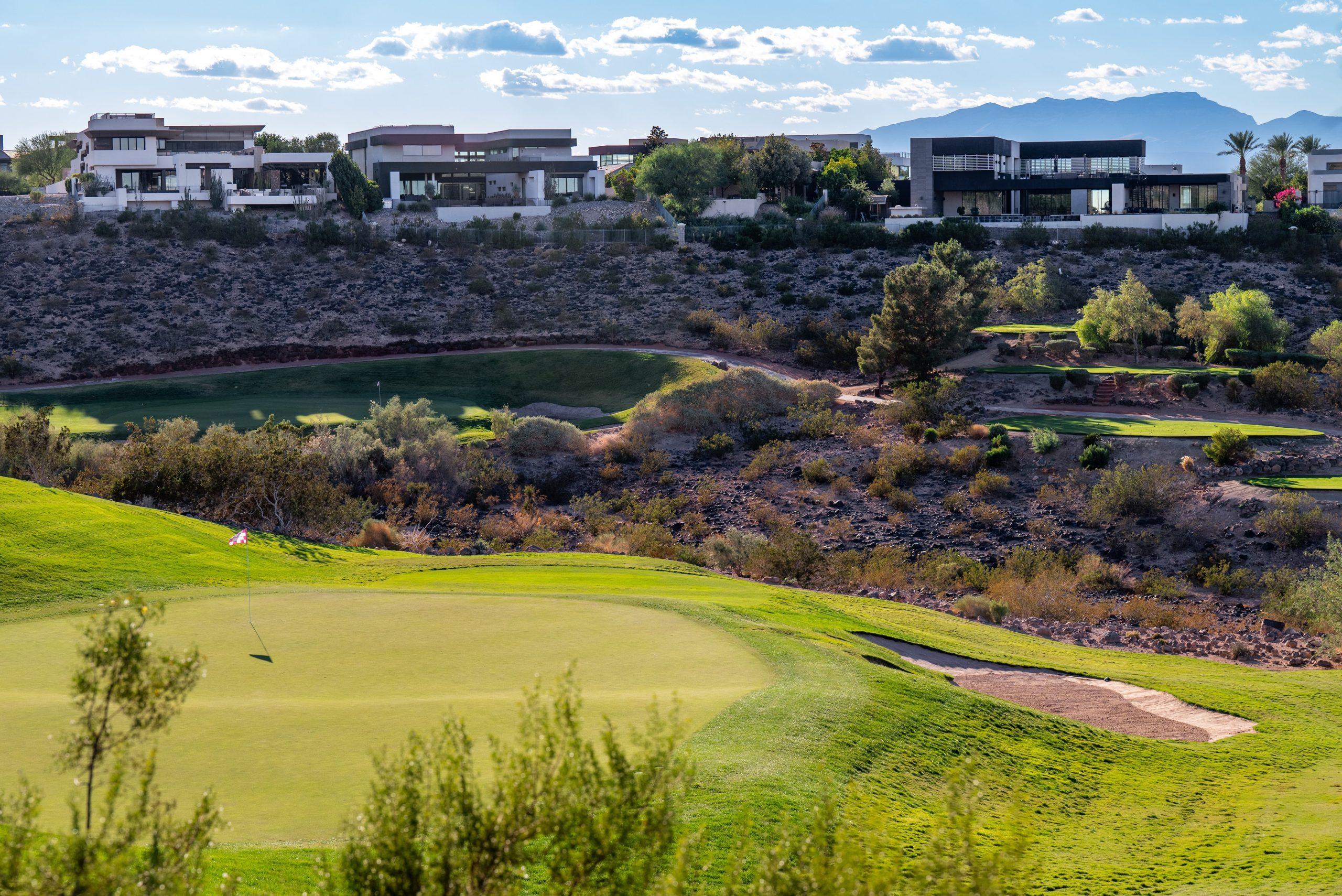 A pristine green at Serket Golf Club framed by desert terrain and luxury modern homes.