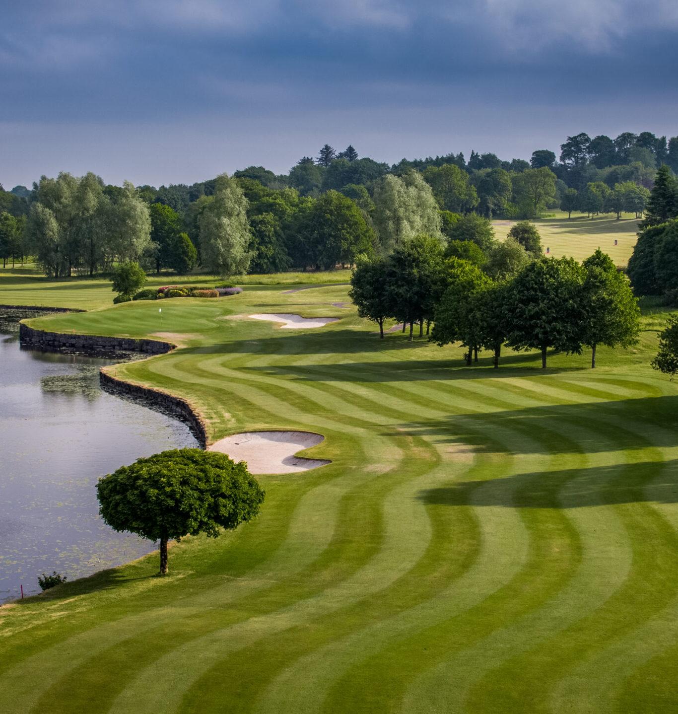 Well-kept green at Slieve Russell with bunkers and trees overlooking a body of water