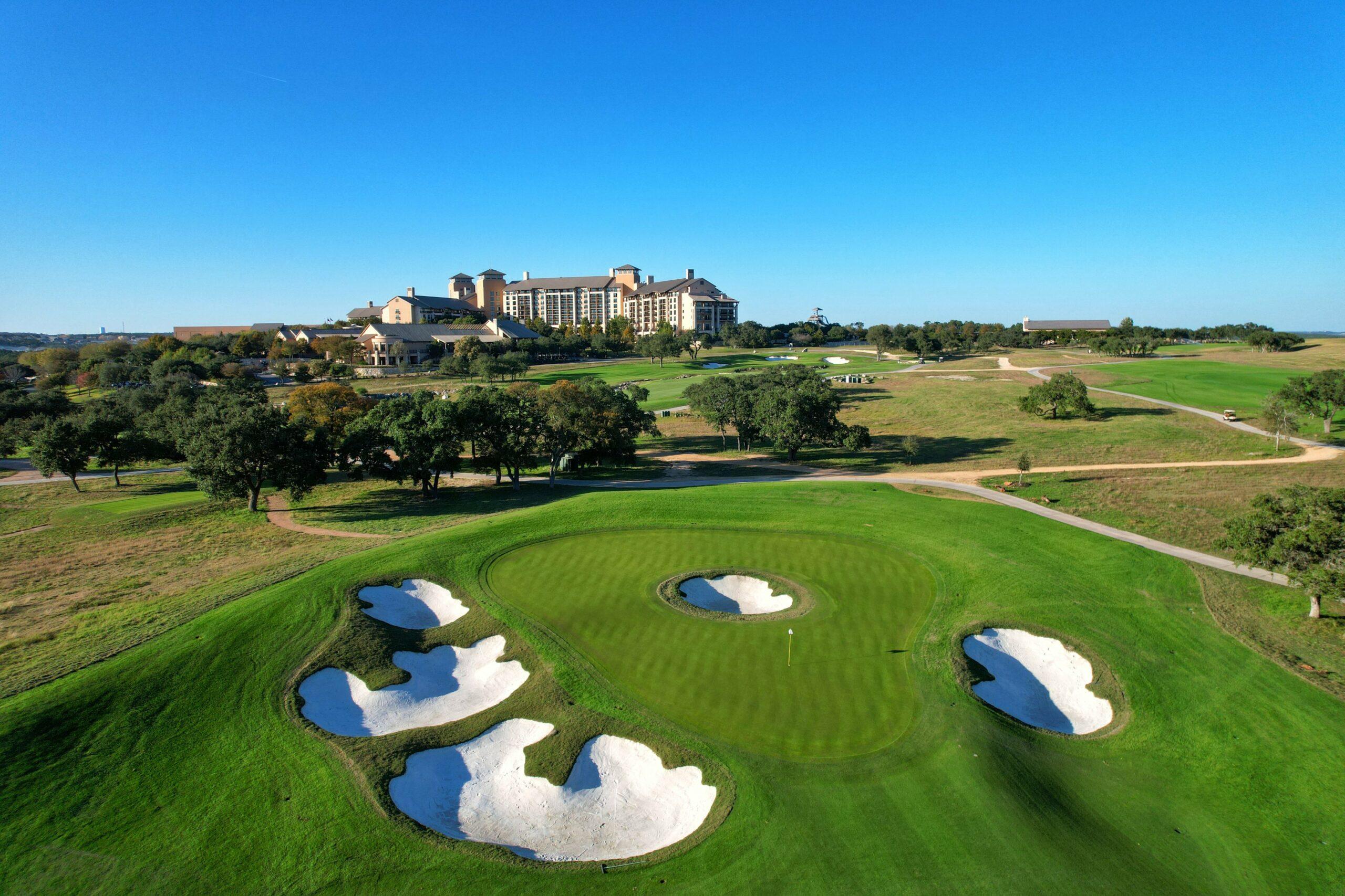 Iconic golf green surrounded by deep white sand bunkers with a luxury resort backdrop.