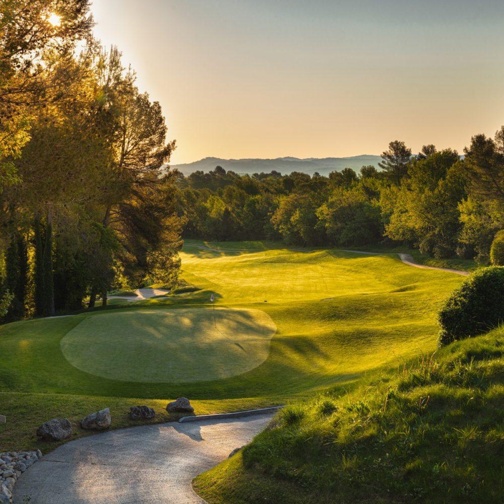 Winding, tree-lined fairway leading to an undulating green