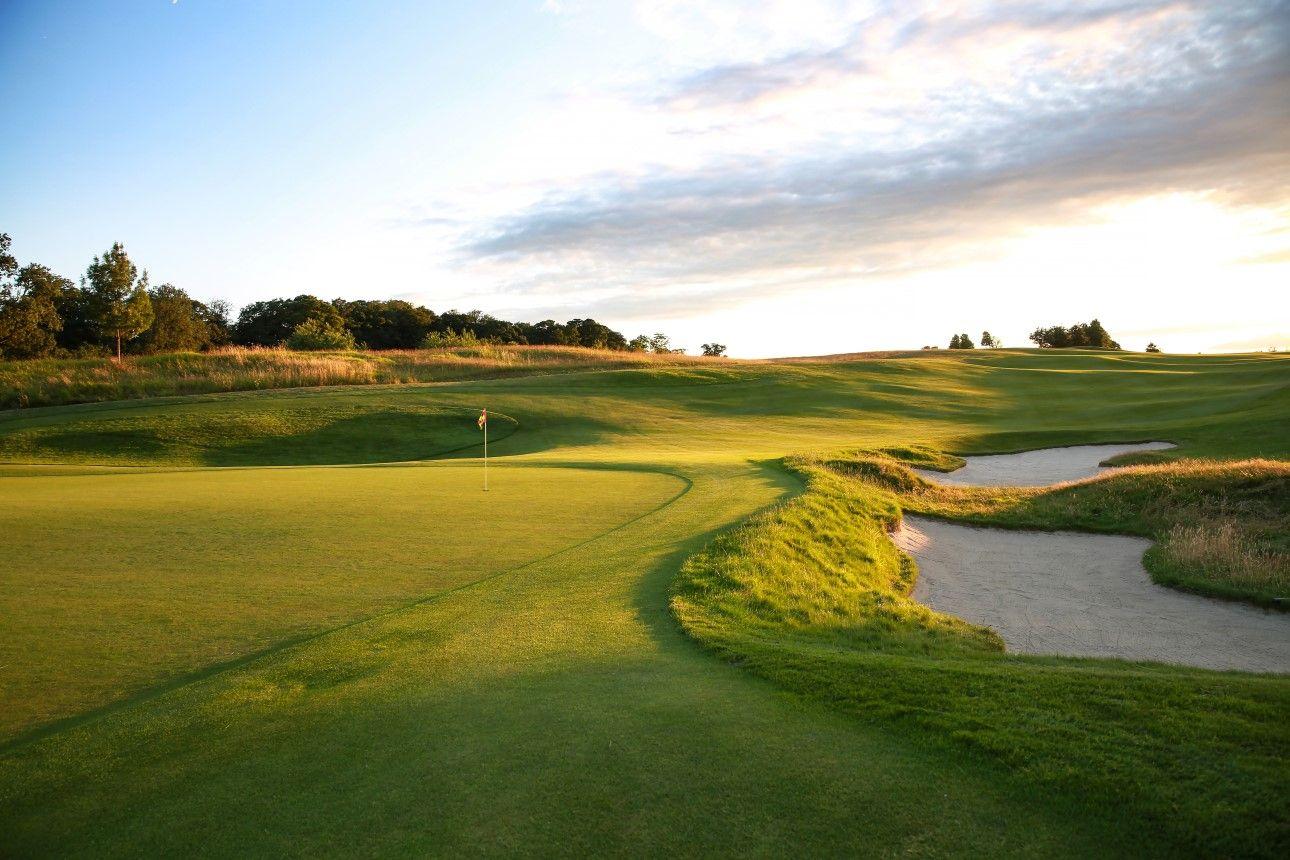 Sun setting over the manicured green and rolling dunes at The Grove course