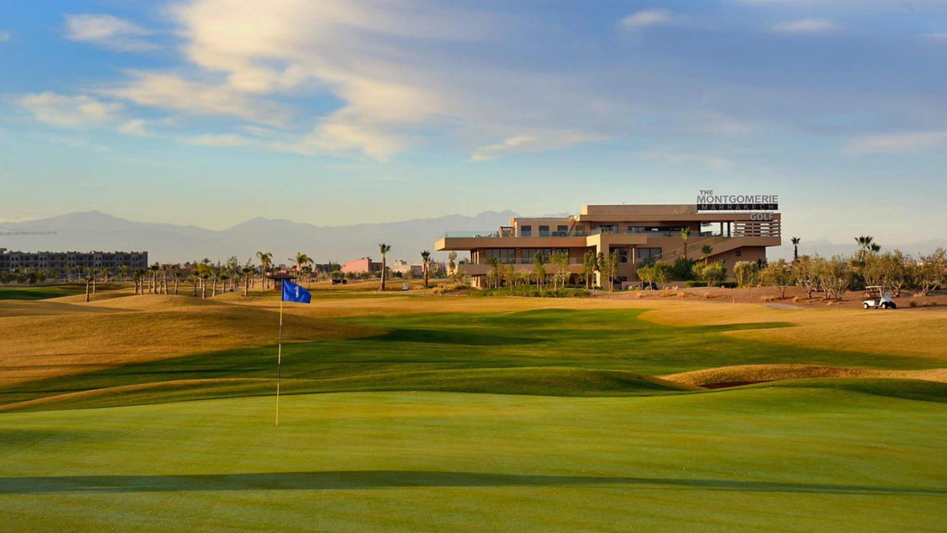 The Montgomerie clubhouse overlooking a smooth green surrounded by a yellow rough