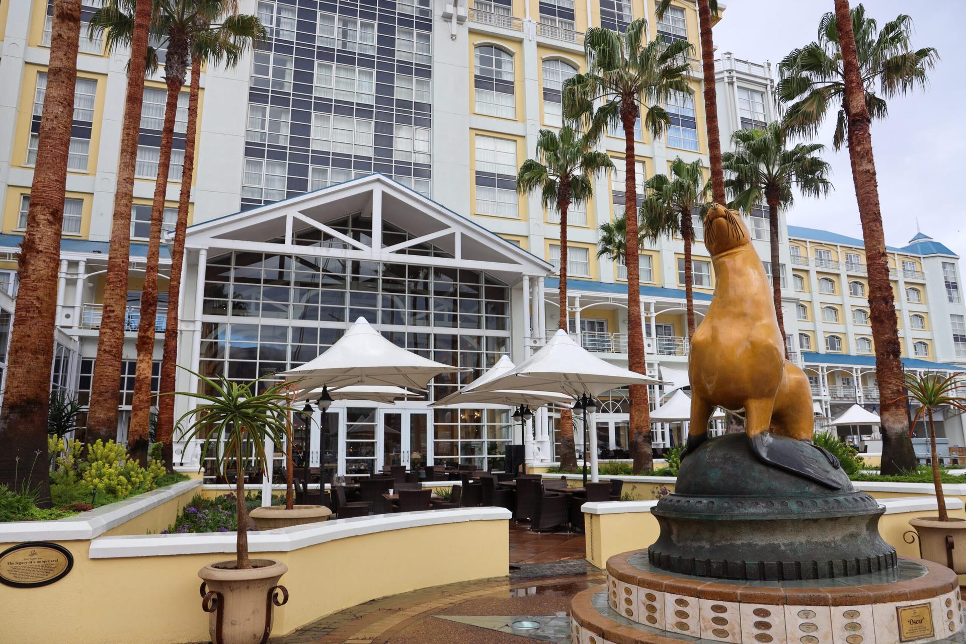 Exterior view of the The Table Bay Hotel building with a gold seal sculpture outside