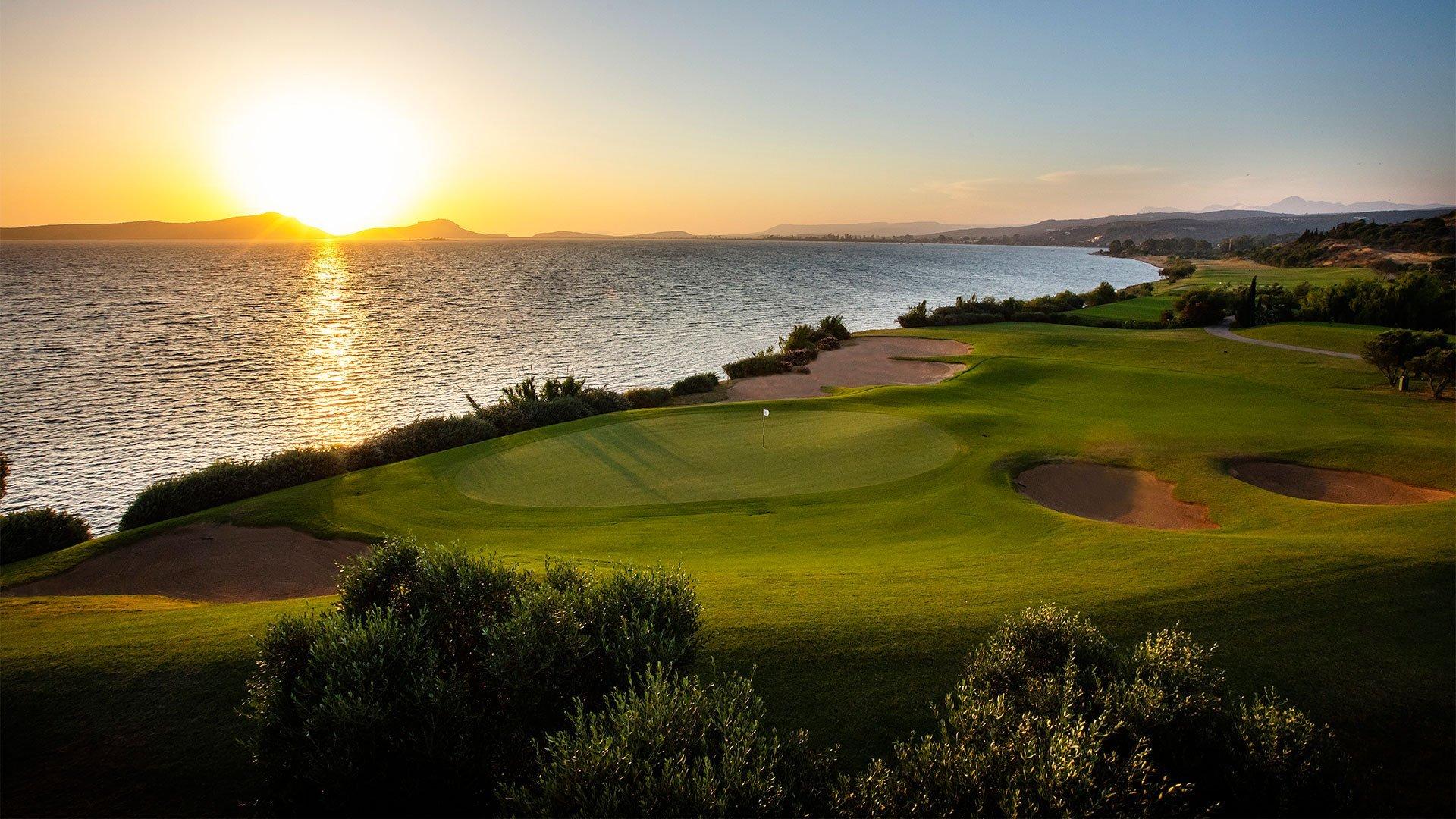 Sun setting over a well maintained green nestled with sand bunkers at The Bay Course