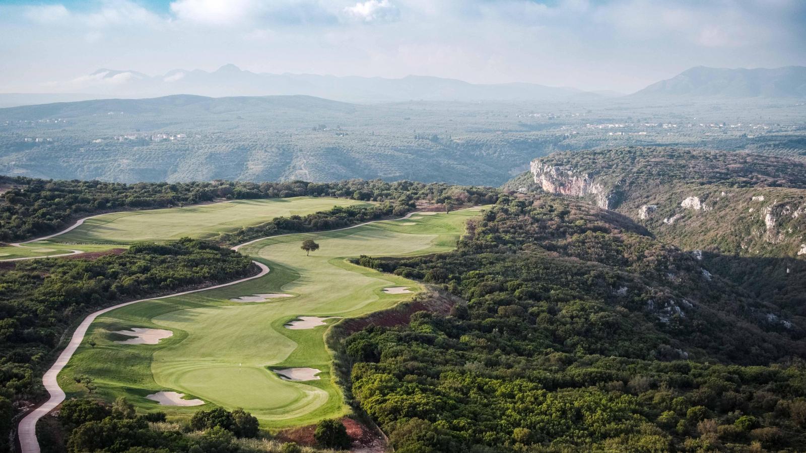 Expansive fairways nestled between forested hills and dramatic cliffs.
