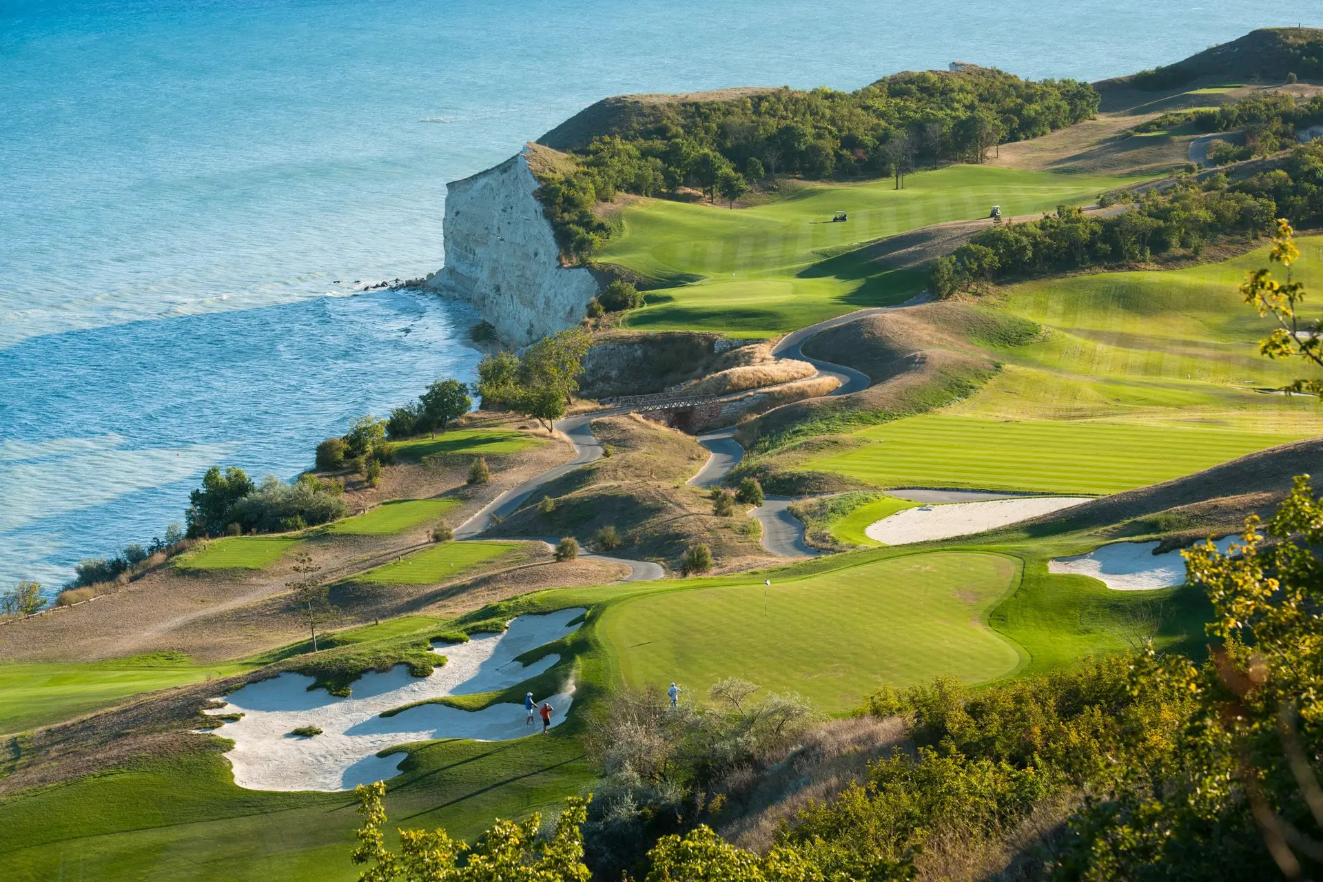 Aerial view of golfers enjoying their round on a green surrounded by large sand bunkers