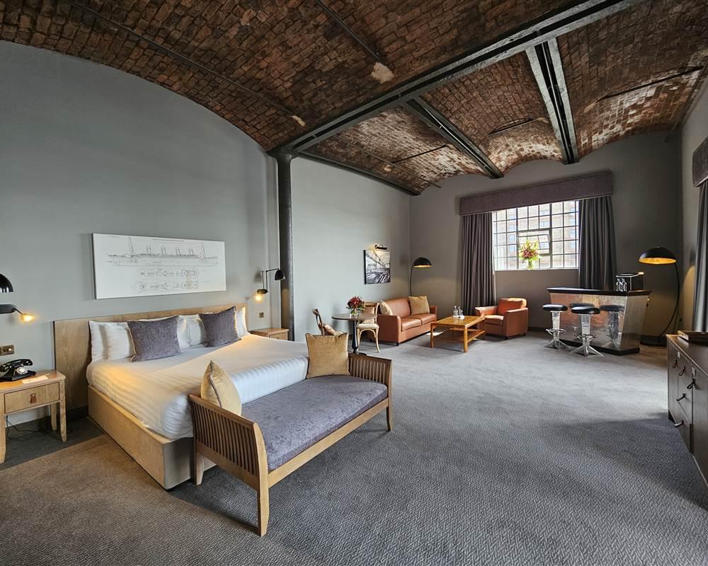 Spacious double bed room at the hotel equipped with a sofa seating area, private bar and large window