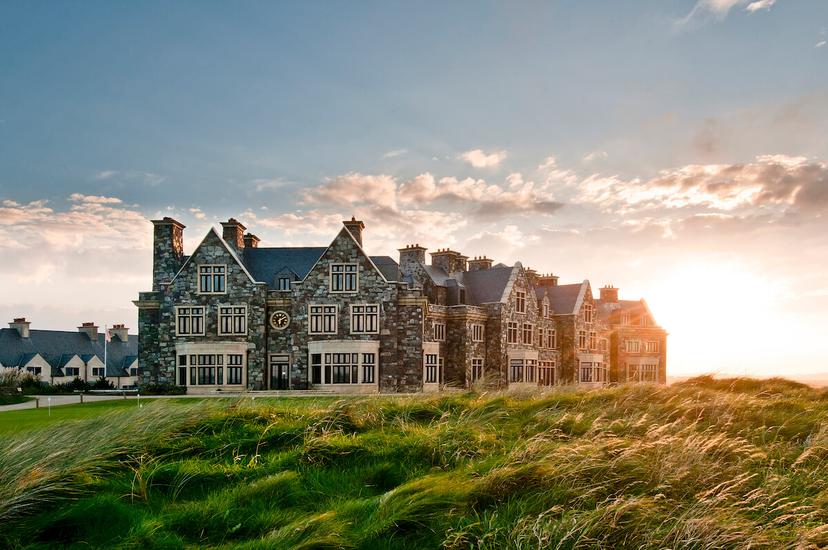 The iconic Trump Doonbeg resort at sunset, framed by windswept dunes.