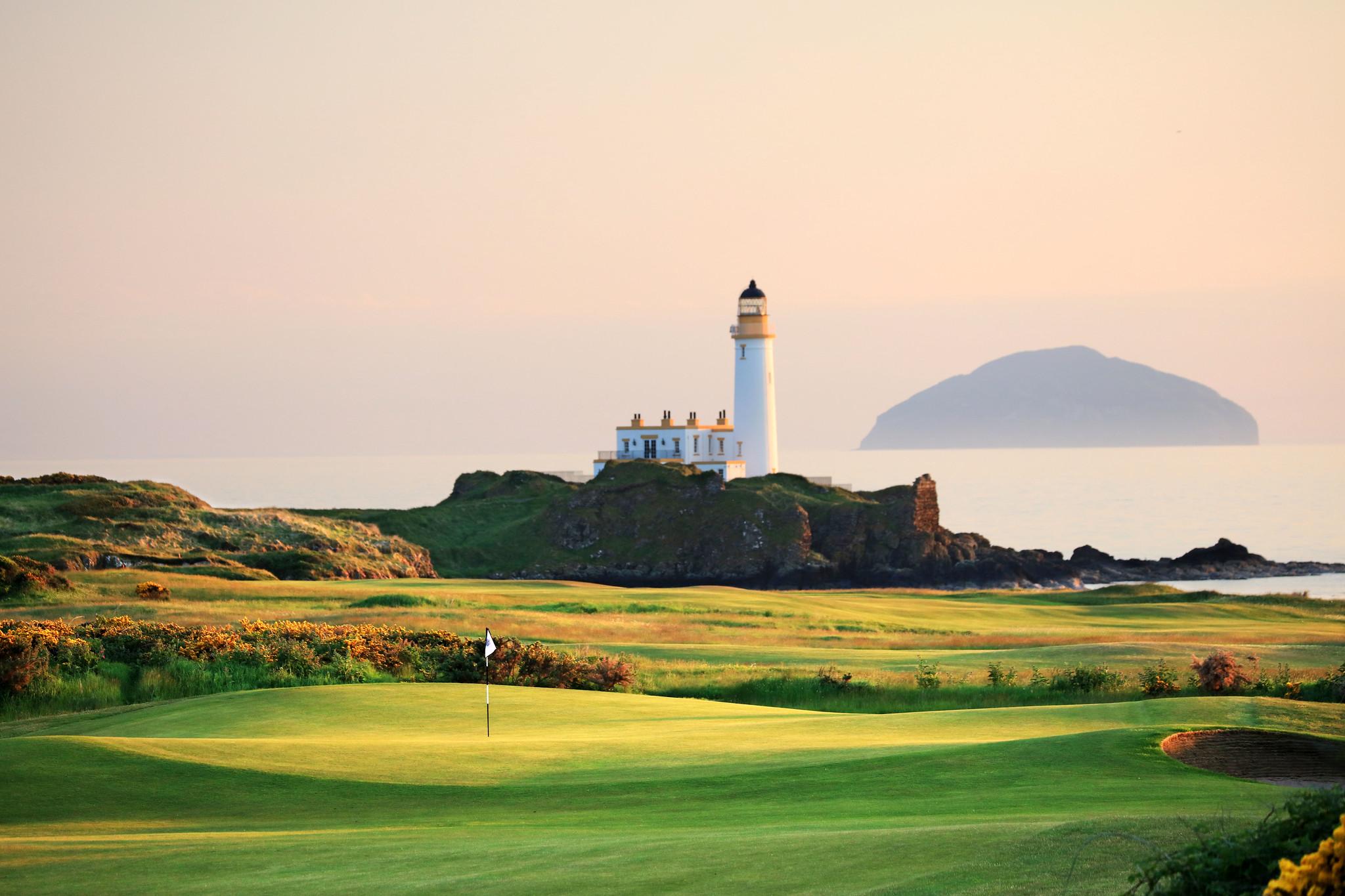 A sunset glow over the lighthouse and golf course with the ocean in the background.