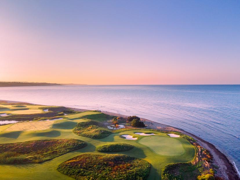 Golf greens beautifully lit by the sunset, merging seamlessly with the shoreline.