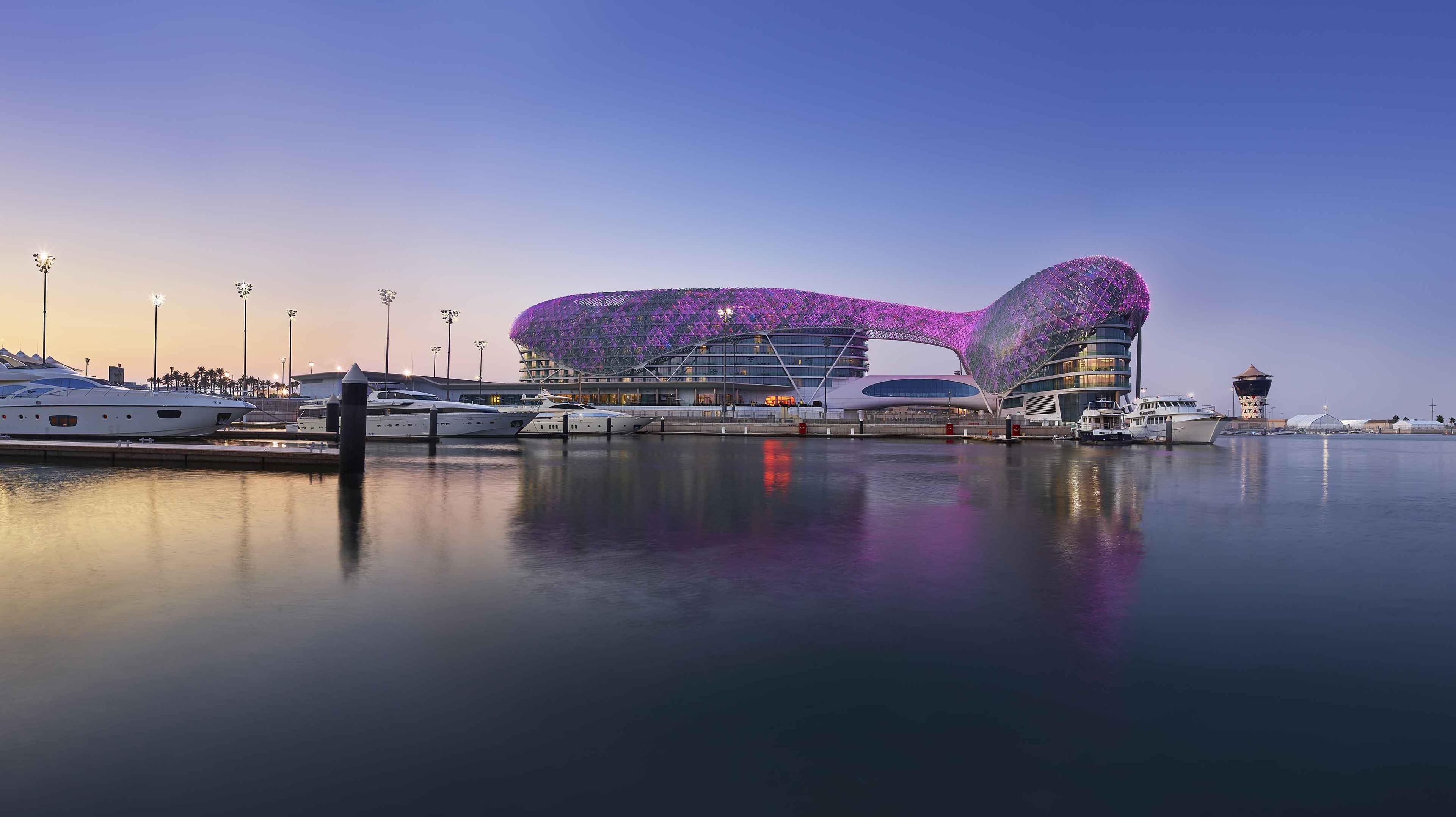 The W Abu Dhabi Yas Island hotel illuminated by purple light next to the dockyard
