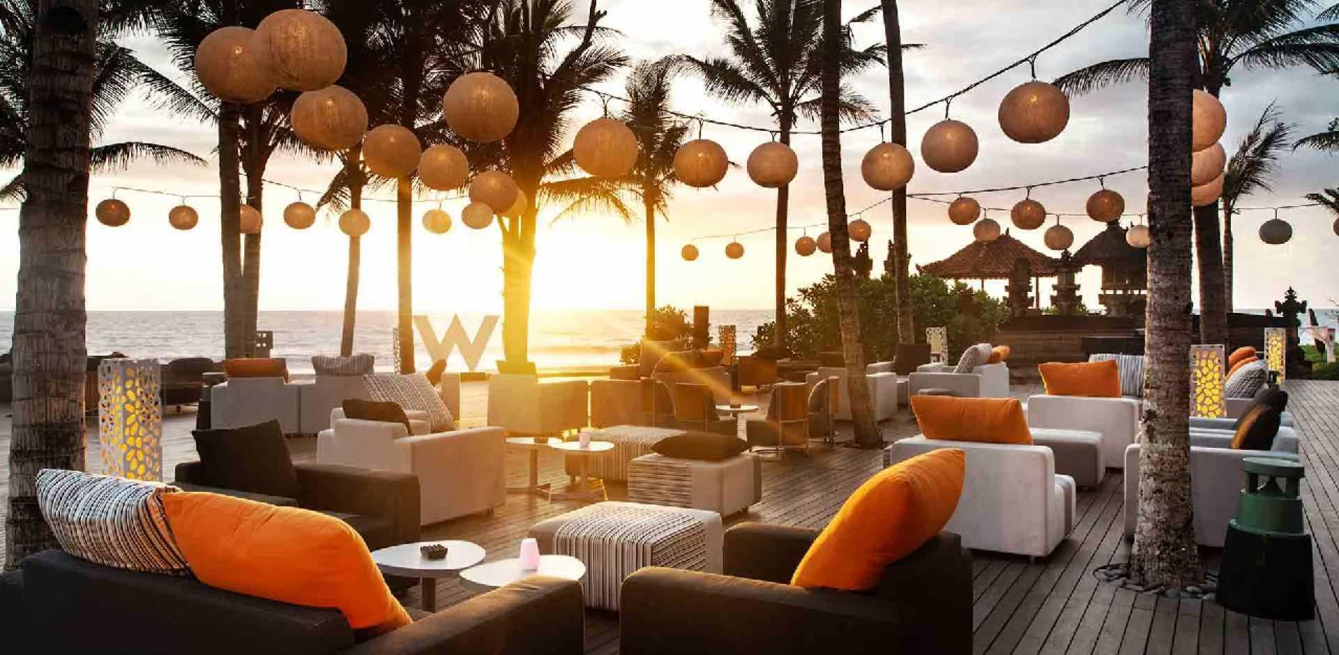The sun setting over an outdoor seating area at the W hotel with their sign in the distance