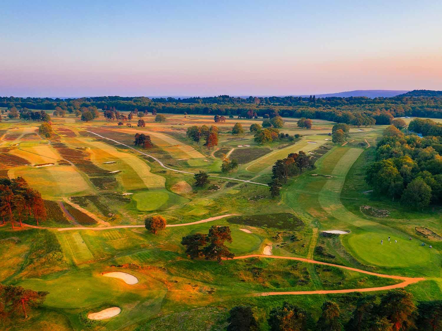 Birseye view of the wide fairways and golfers putting on the well-kept greens on the Walton Heath Course