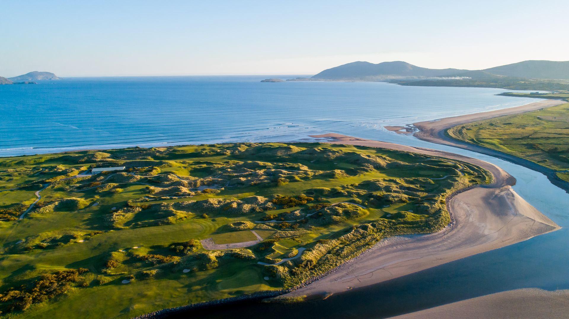 Aerial view of the course with wide fairways overlooking the sea and mountains in the distance