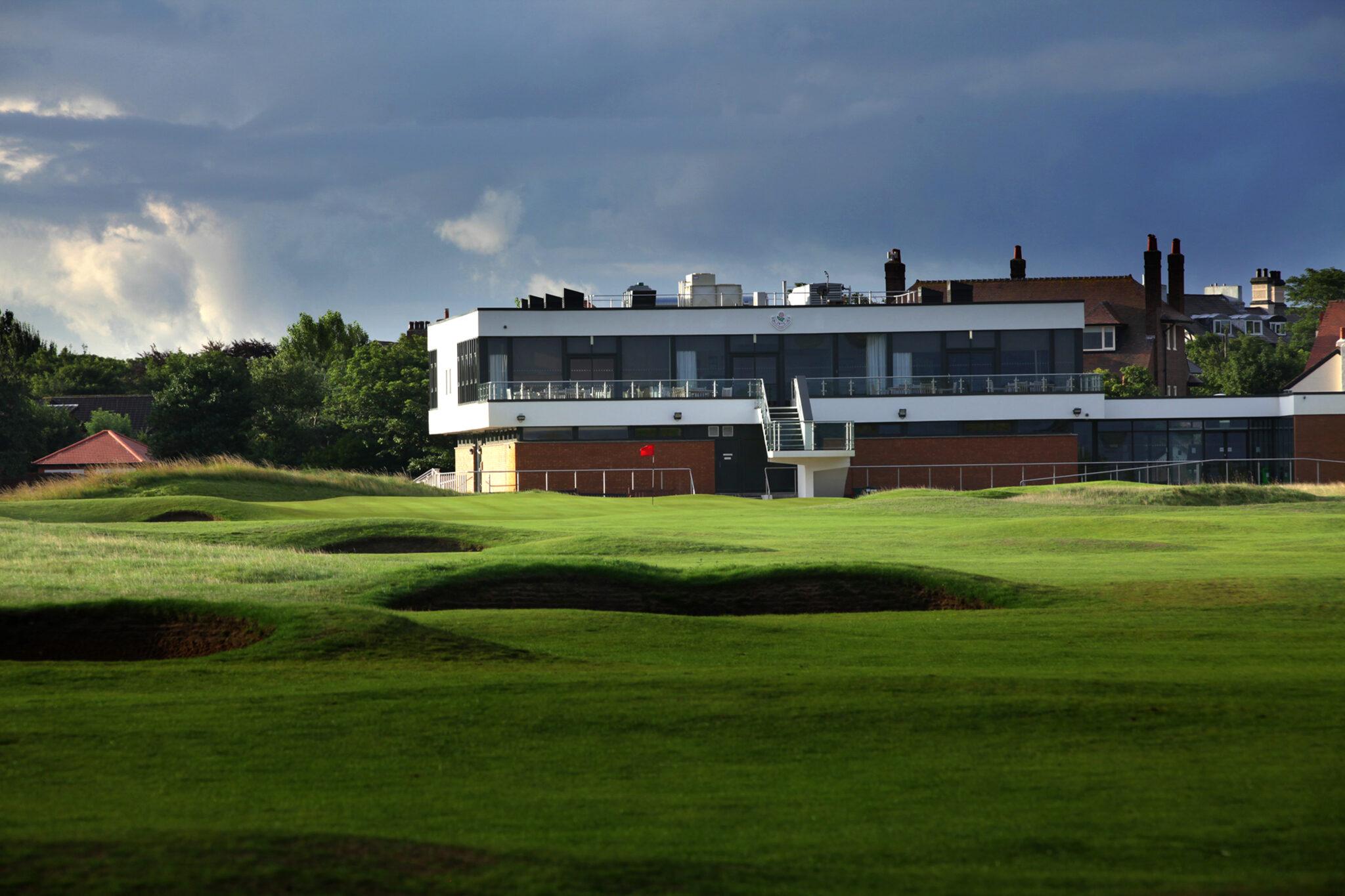 The modern clubhouse overlooking a challenging green surrounded by bunkers.
