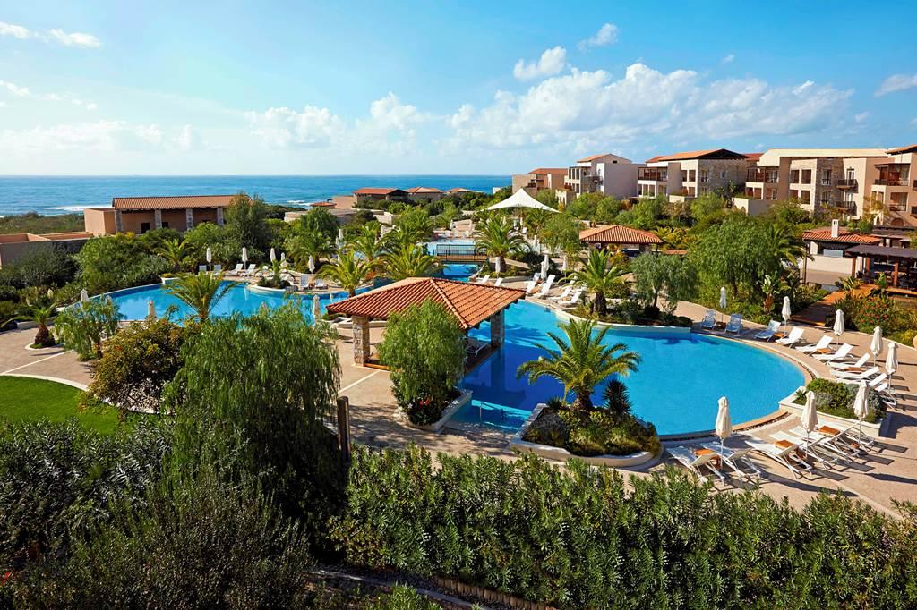 Overhead view of a swimming pool littered with sun beds under blue skies