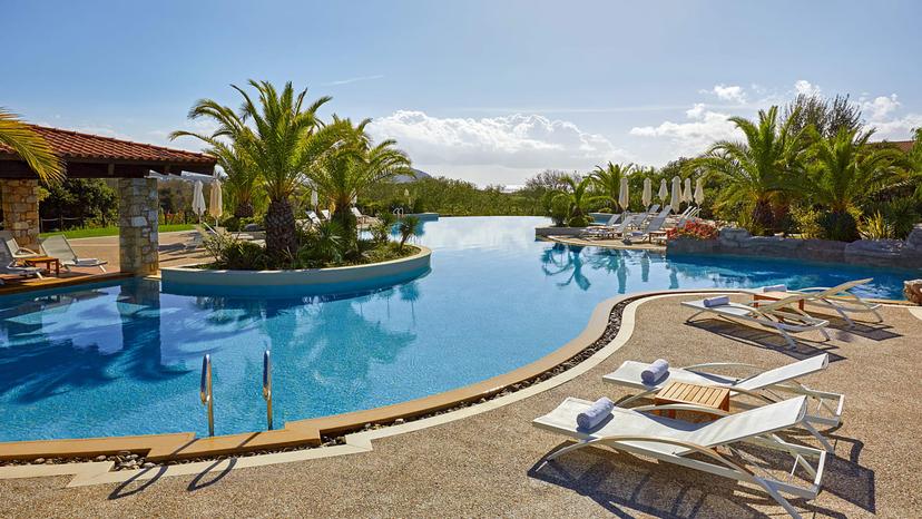 A winding outdoor swimming pool at The Westin Resort Costa Navarino nestled with palm trees