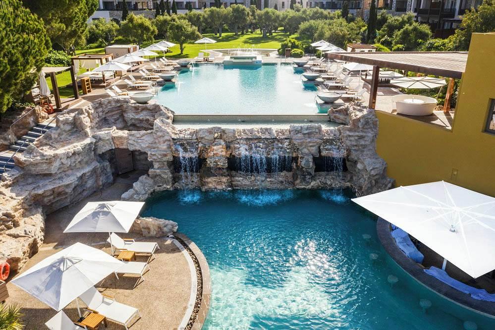 Outdoor infinity pool with a stone water fountain leading to a lower pool