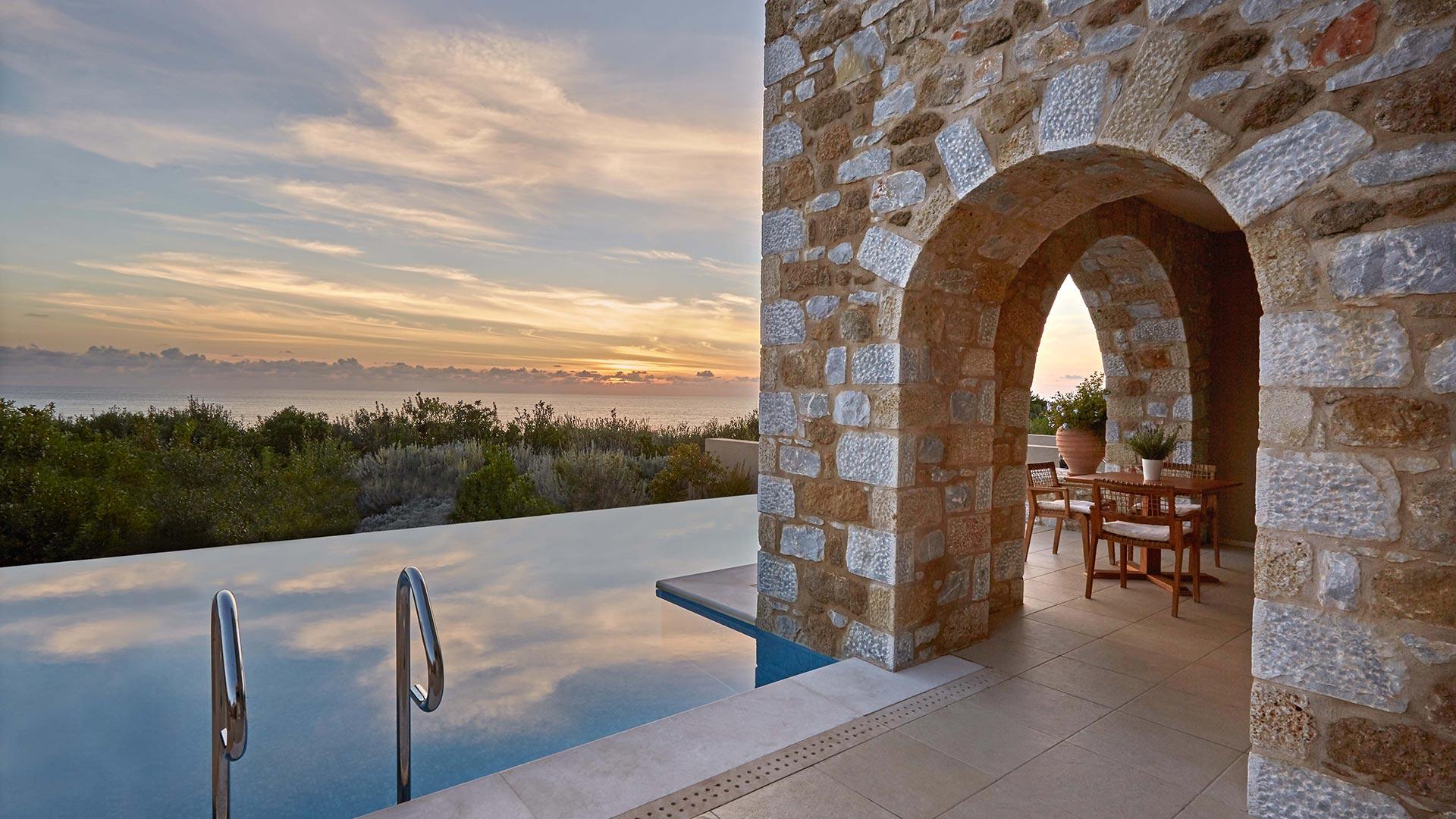 An infinity pool with coastal views in the sun setting in the background