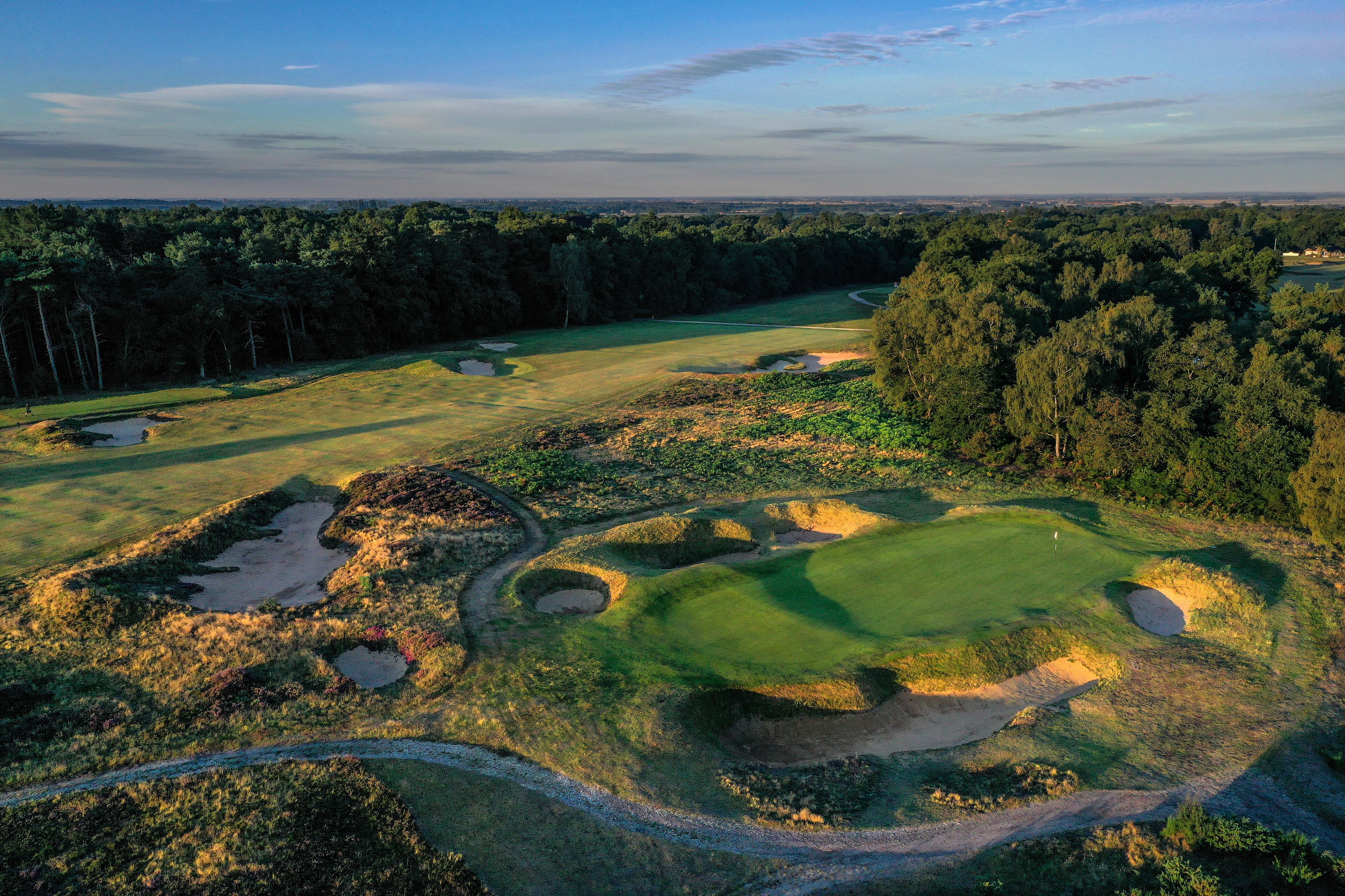 Green with rugged bunkers and forest backdrop.