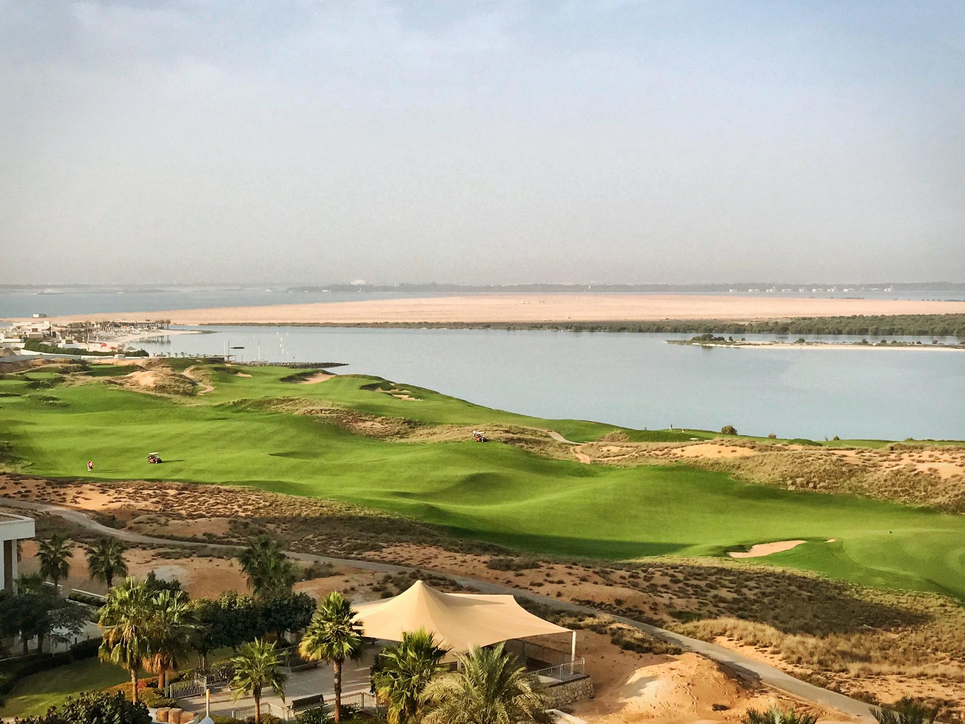 A wide fairway nestled with sand bunkers running along coastal water