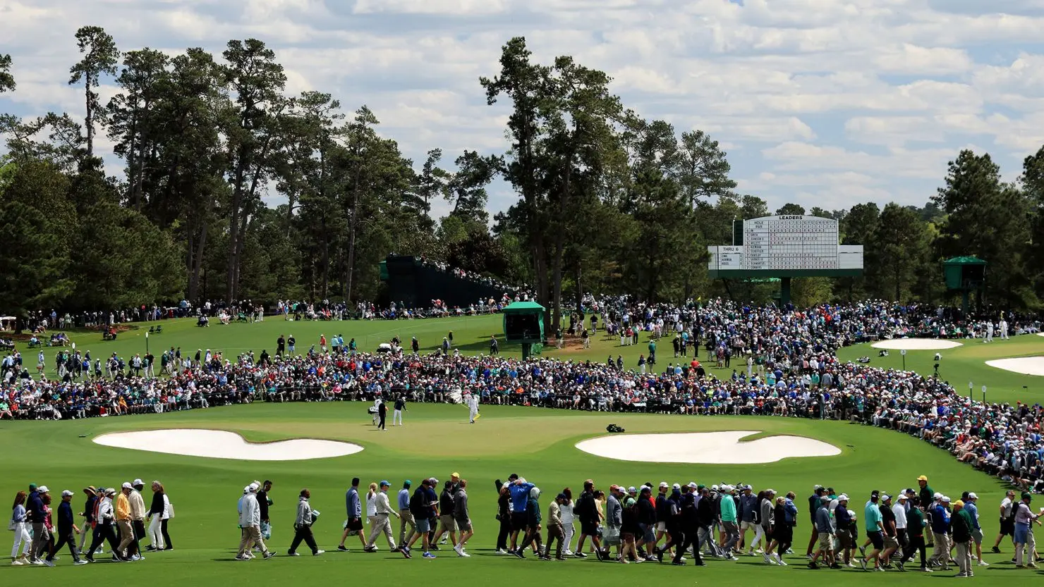 Crowds around Augusta National watching the action with the scoreboard in the background