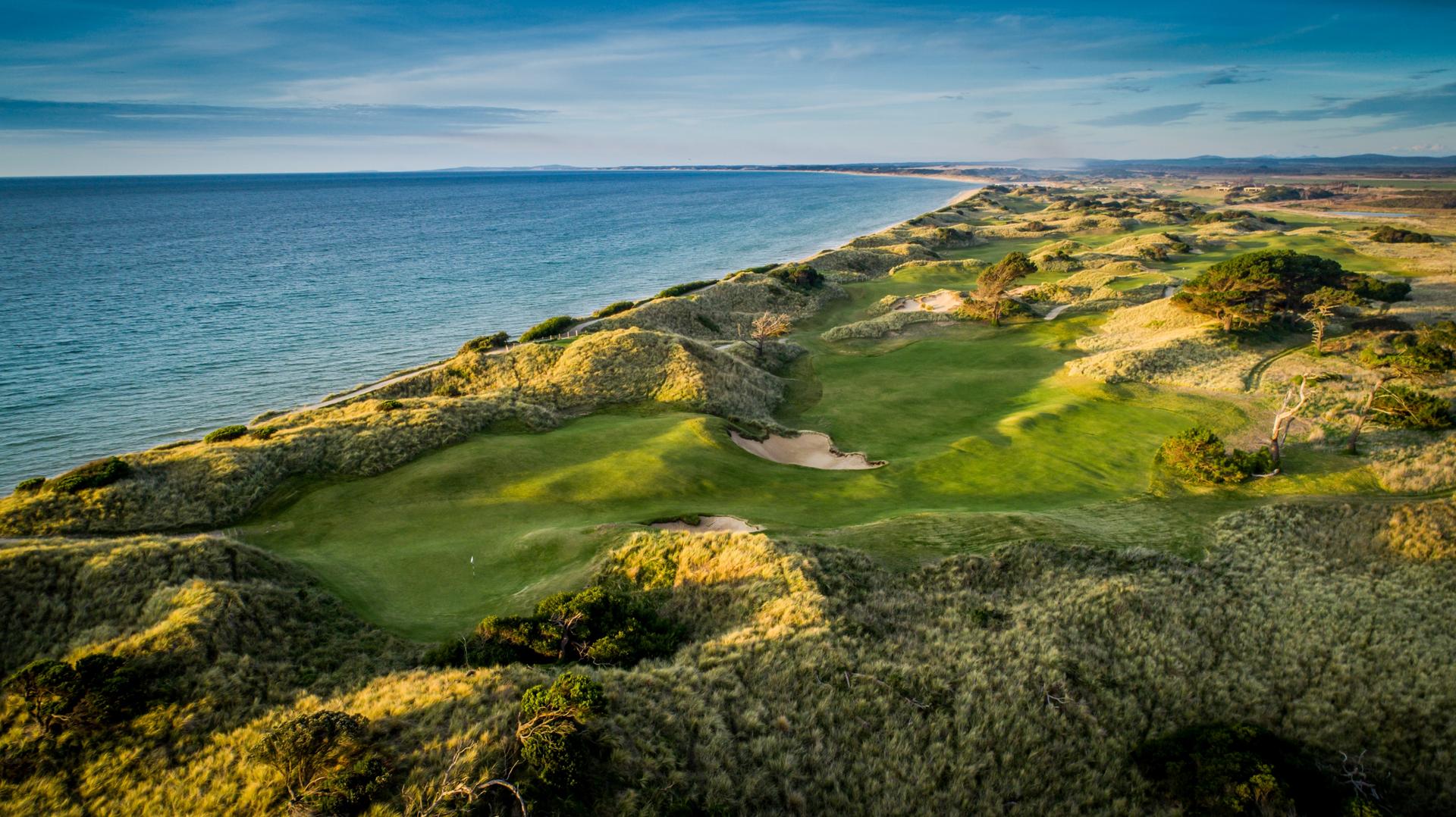 Overhead view of an elevated green with coastal views nestled with sand bunkers