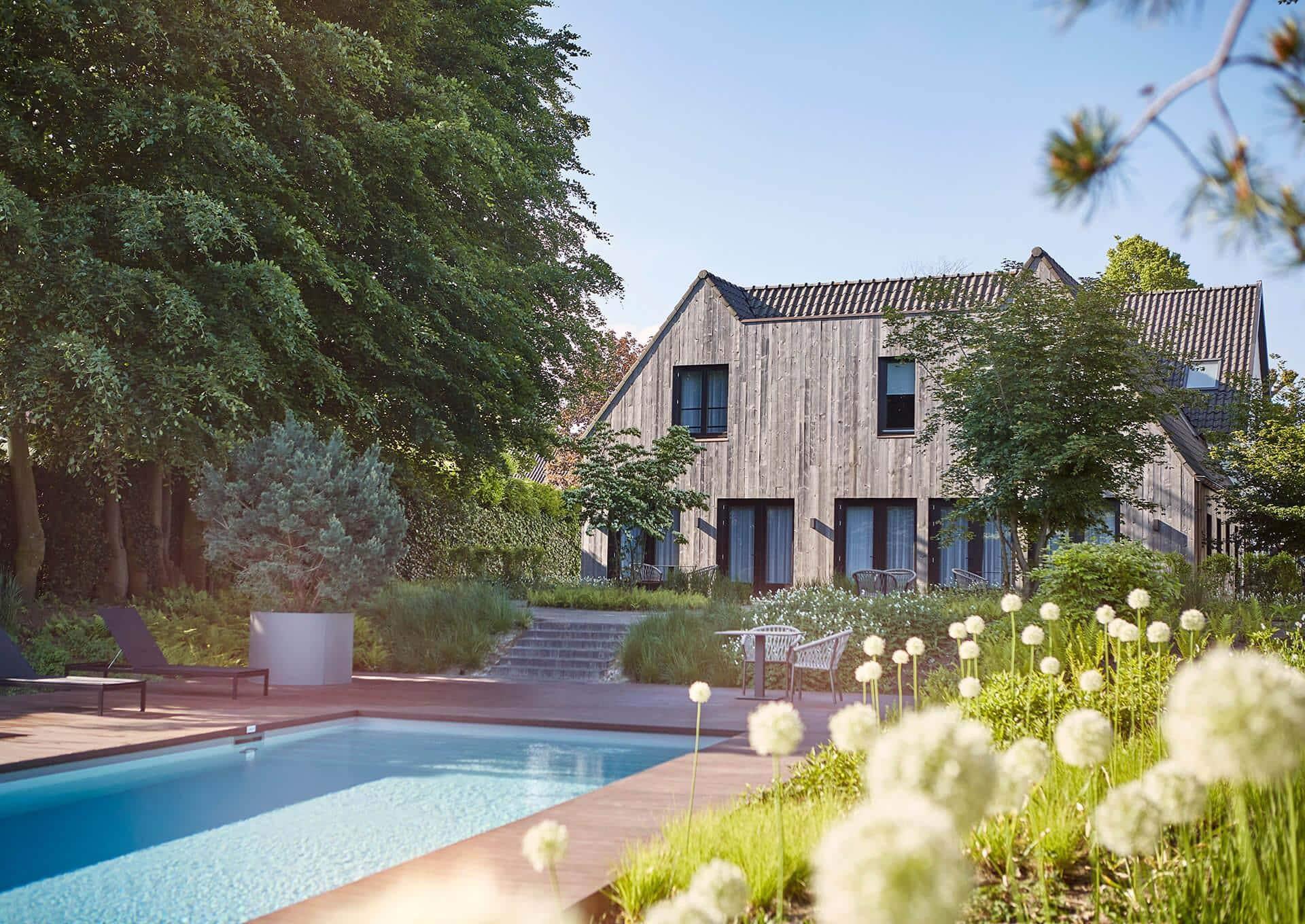 A swimming pool surrounded by sun beds i the garden of a lodge