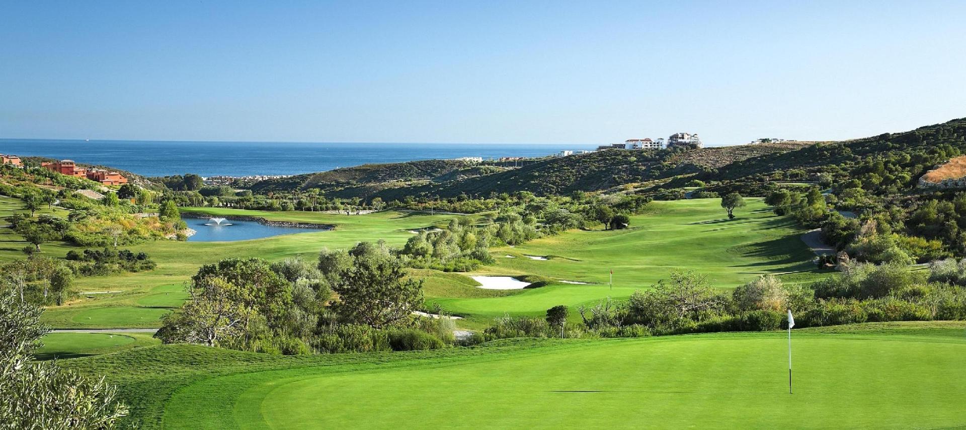 A smooth green overlooking a wide fairway riddled with sand bunkers