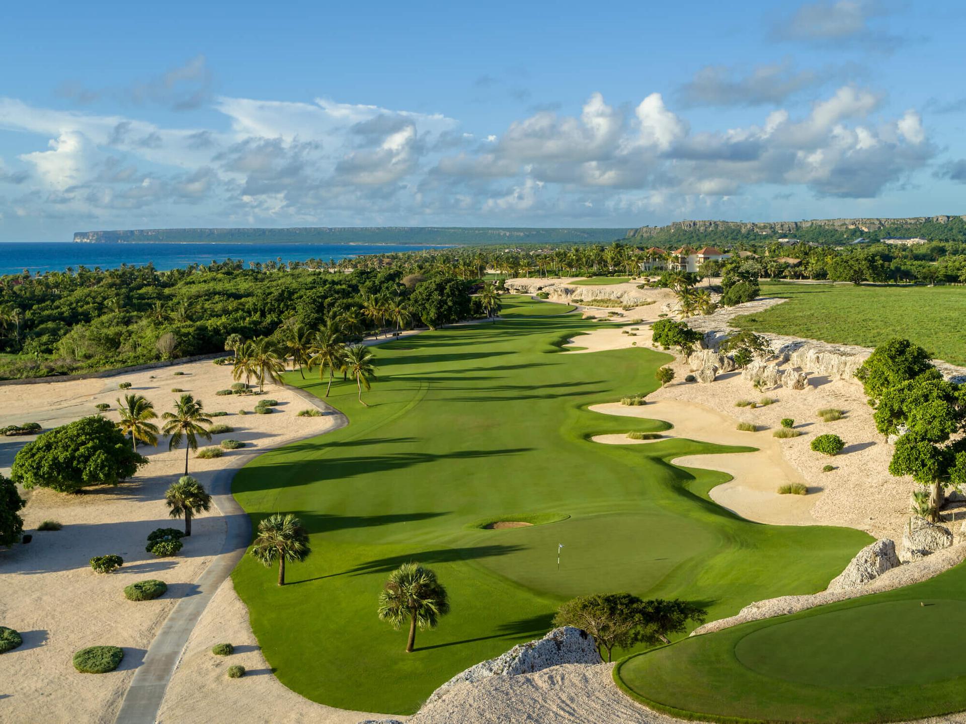 A winding fairway leading to a smooth green surrounded by a sandy rough