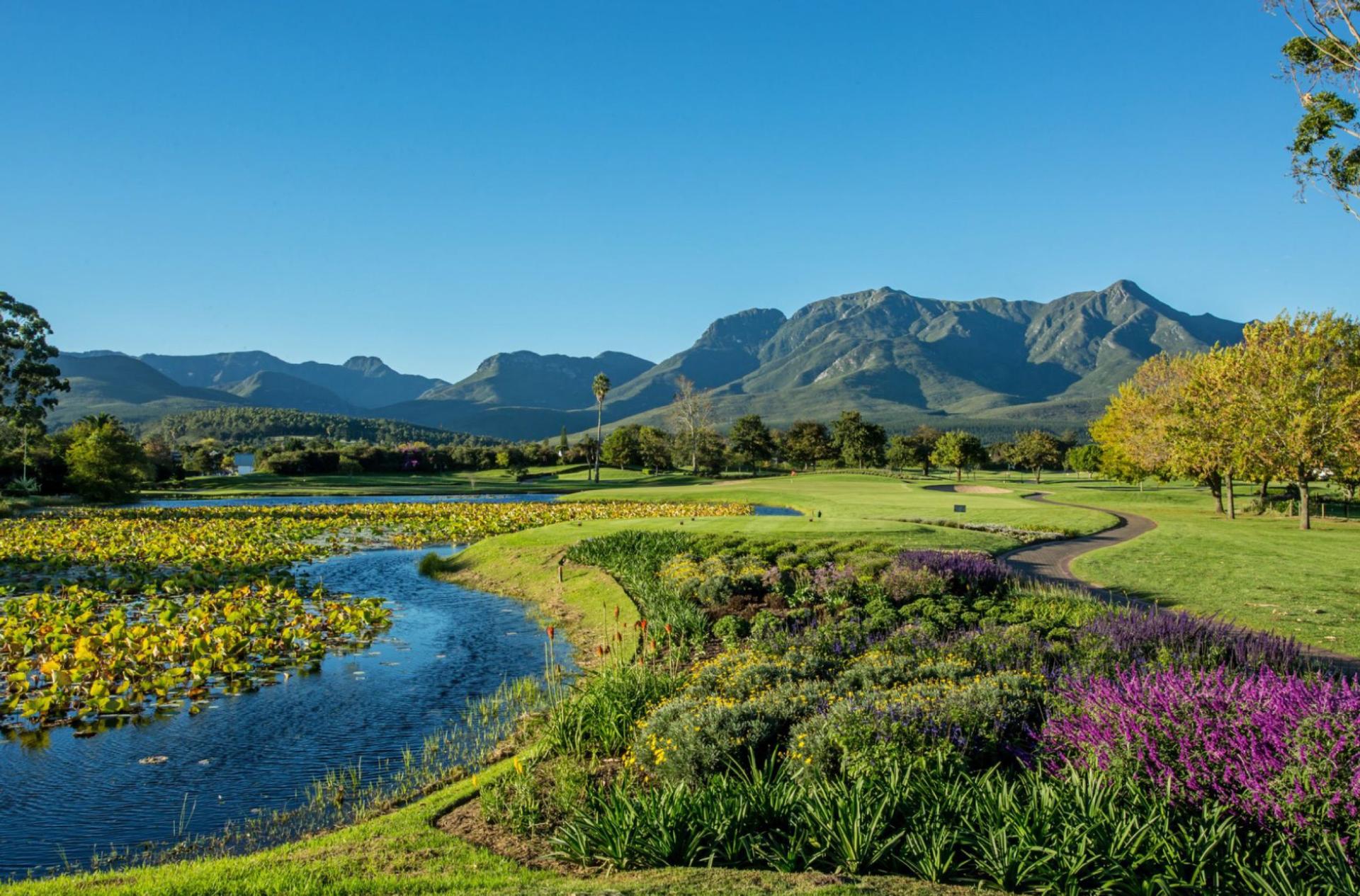 Water hazard on the left with a winding fairway on the right and mountains in the background